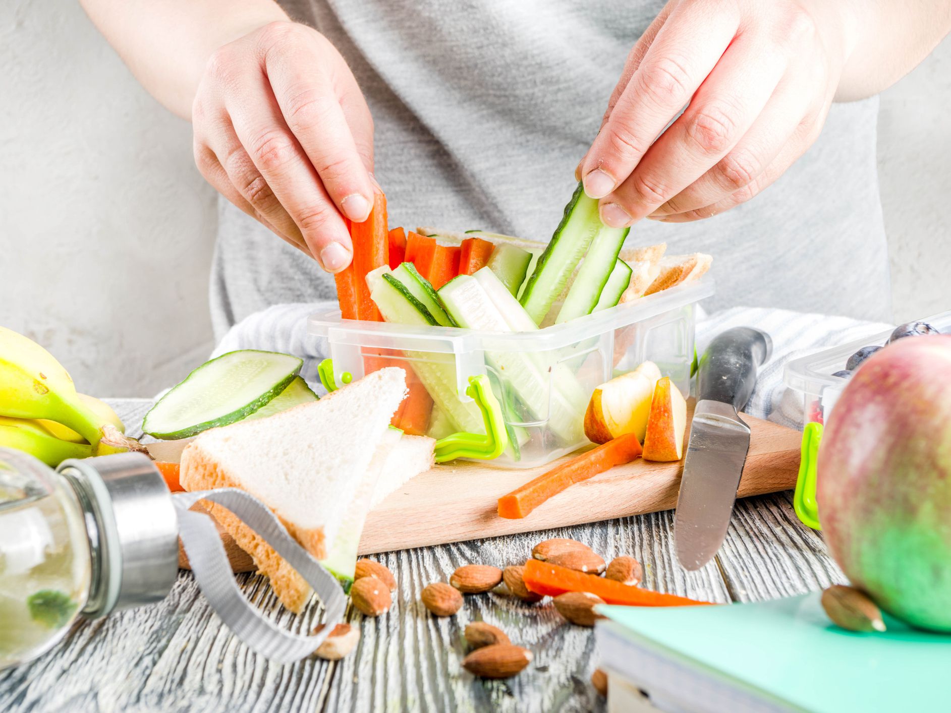 Mother cooking school lunch box set, Preparing healthy snacks-cheese sandwich with cucumber, carrot. Nuts, fruits and vegetable in box.