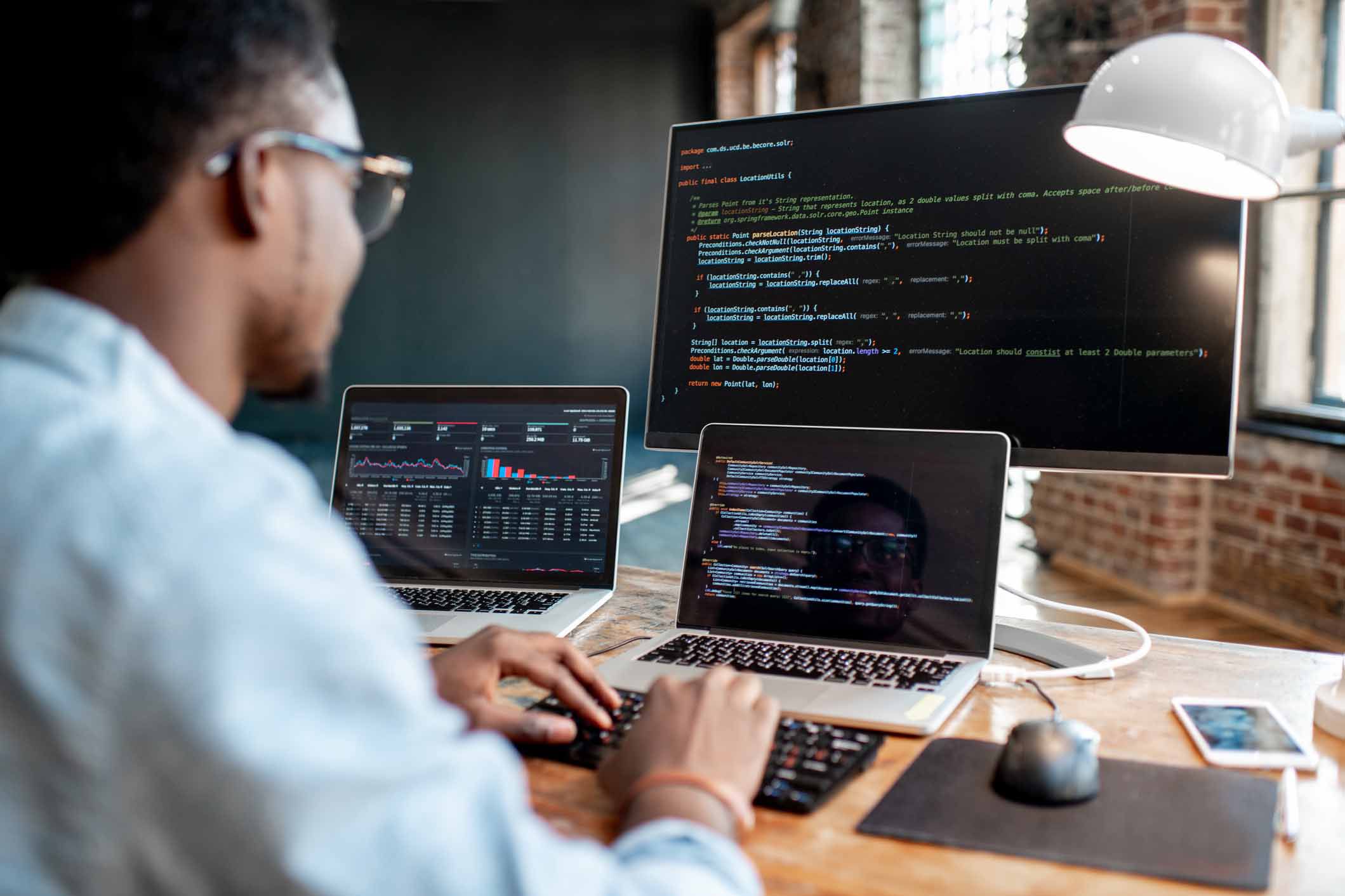 programmer looking at three monitors