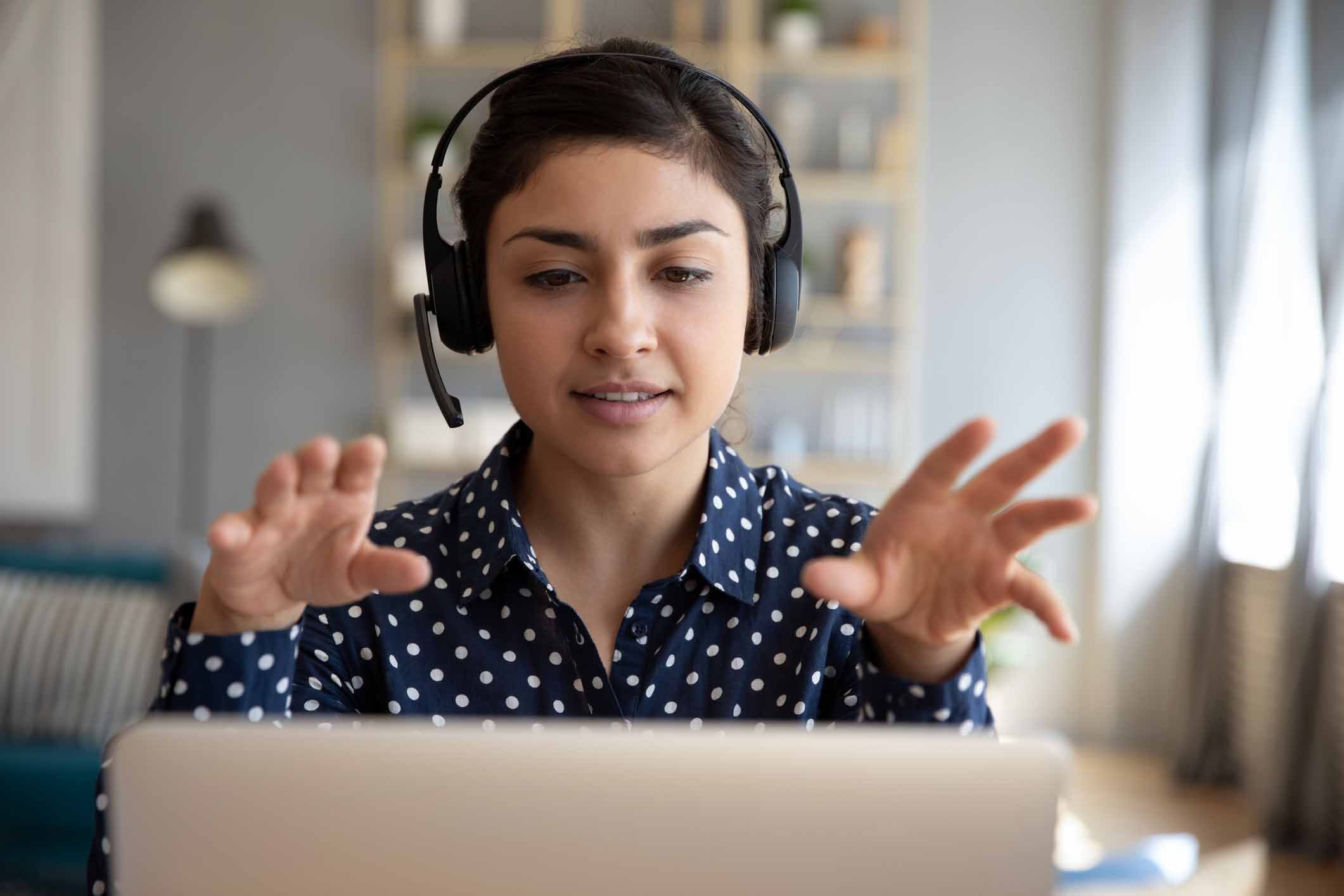 woman in home with headset looking at computer
