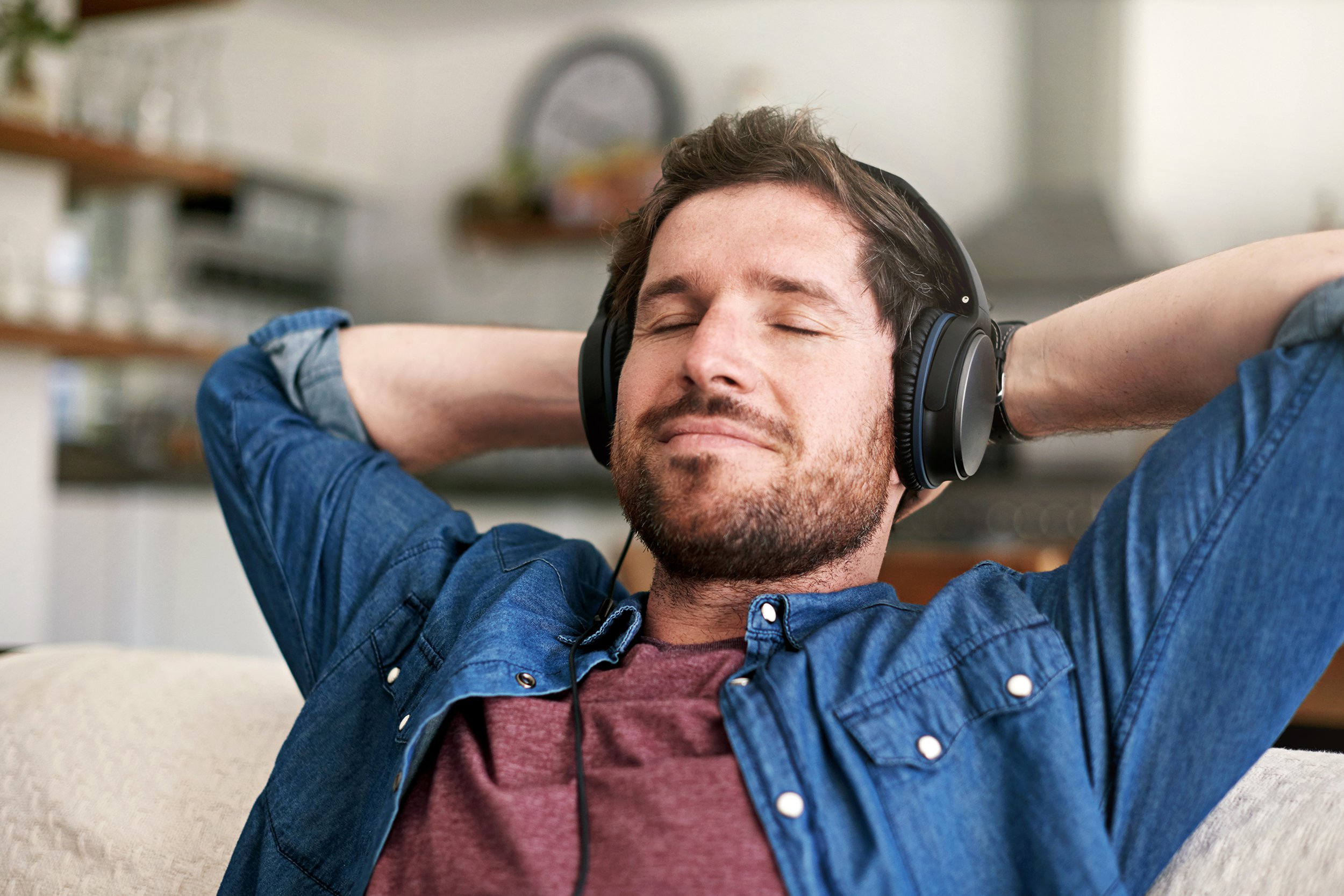 man listing to calming music on headphones in home