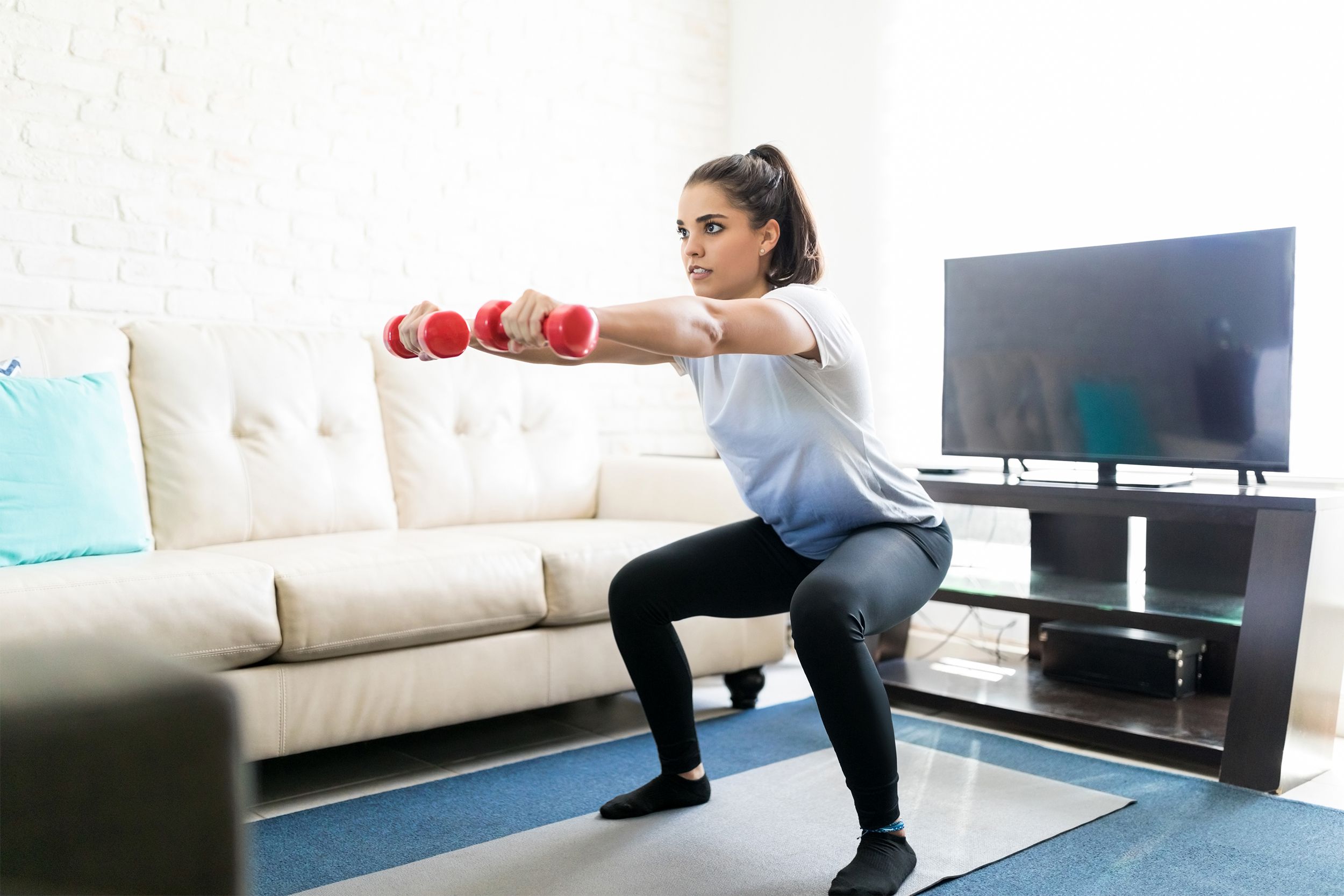 Woman doing squats with weights in her living room