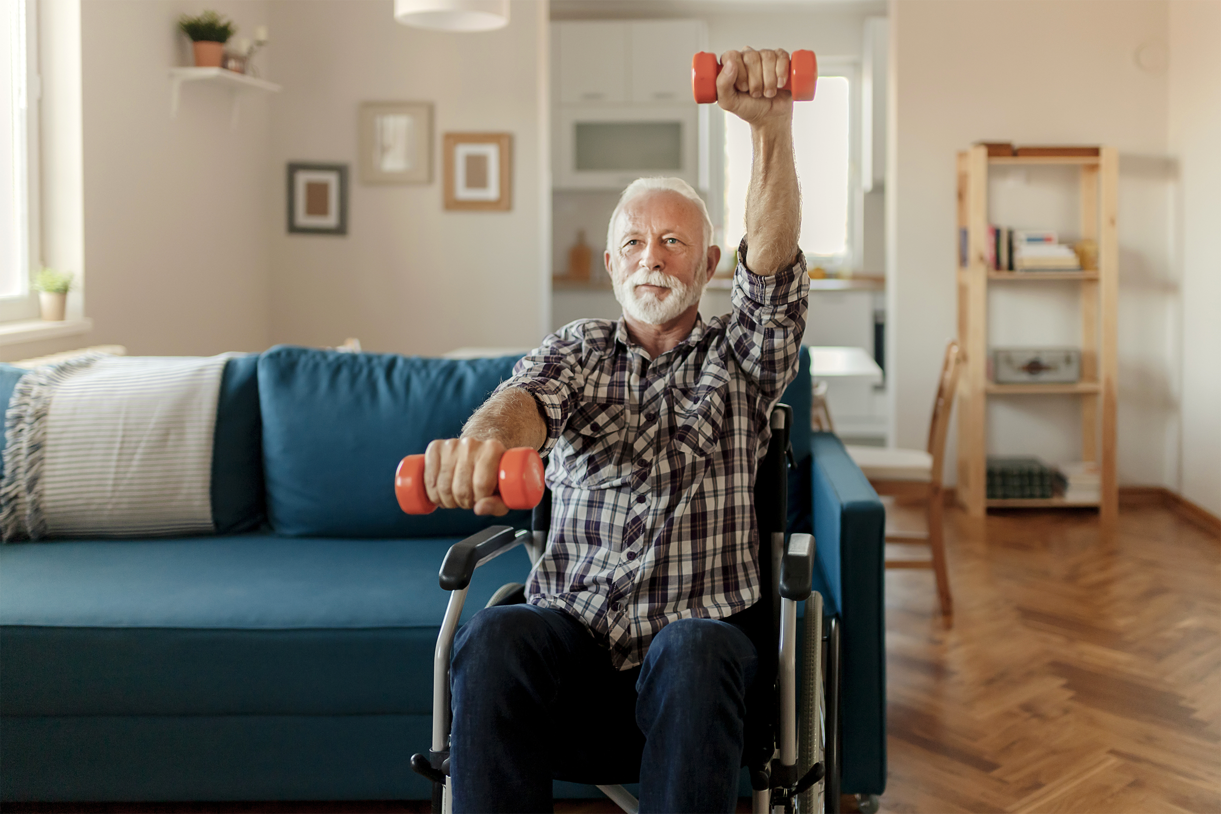 Senior man lifting dumbbells at home in his wheelchair