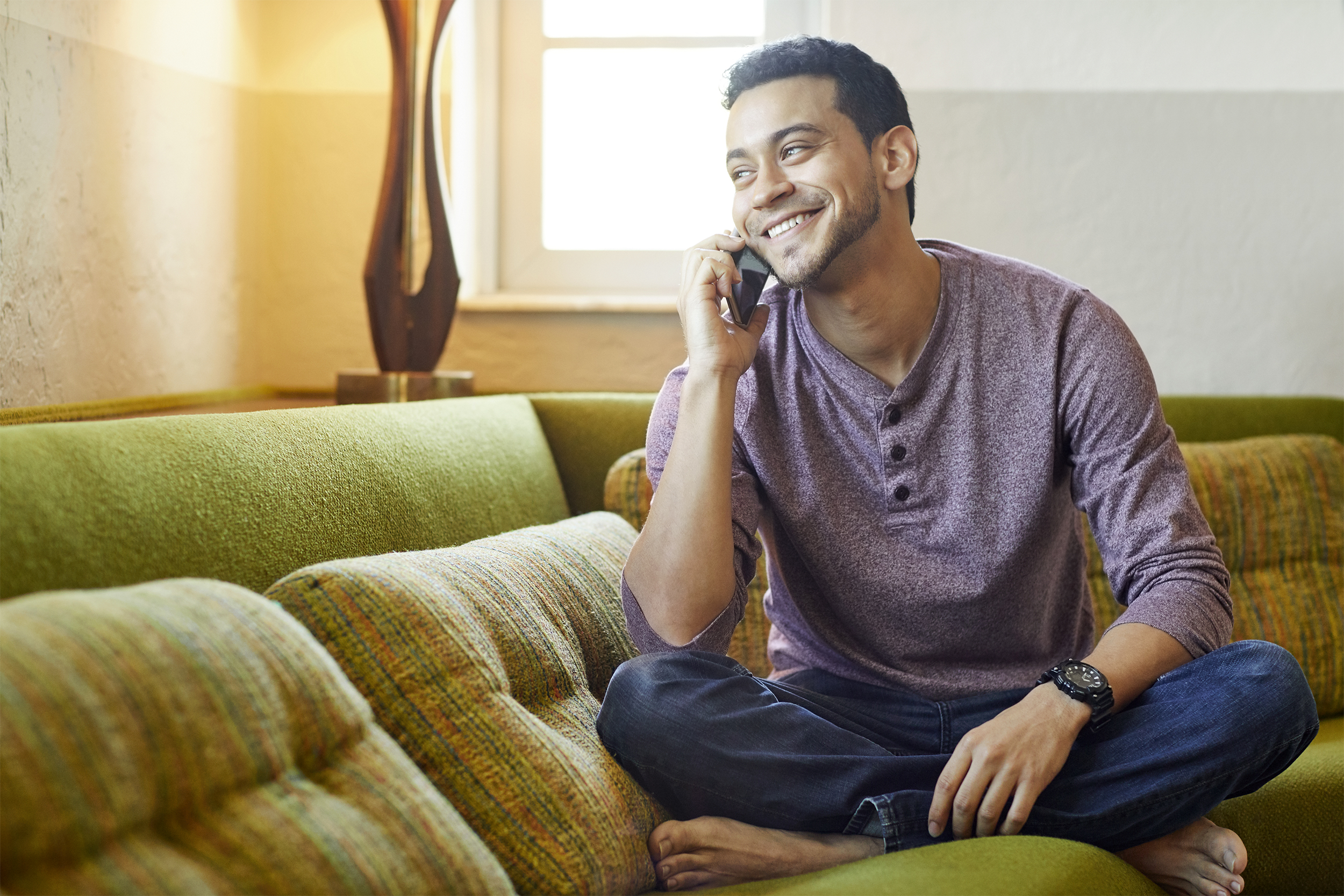 Man smiling and talking on the phone on his couch