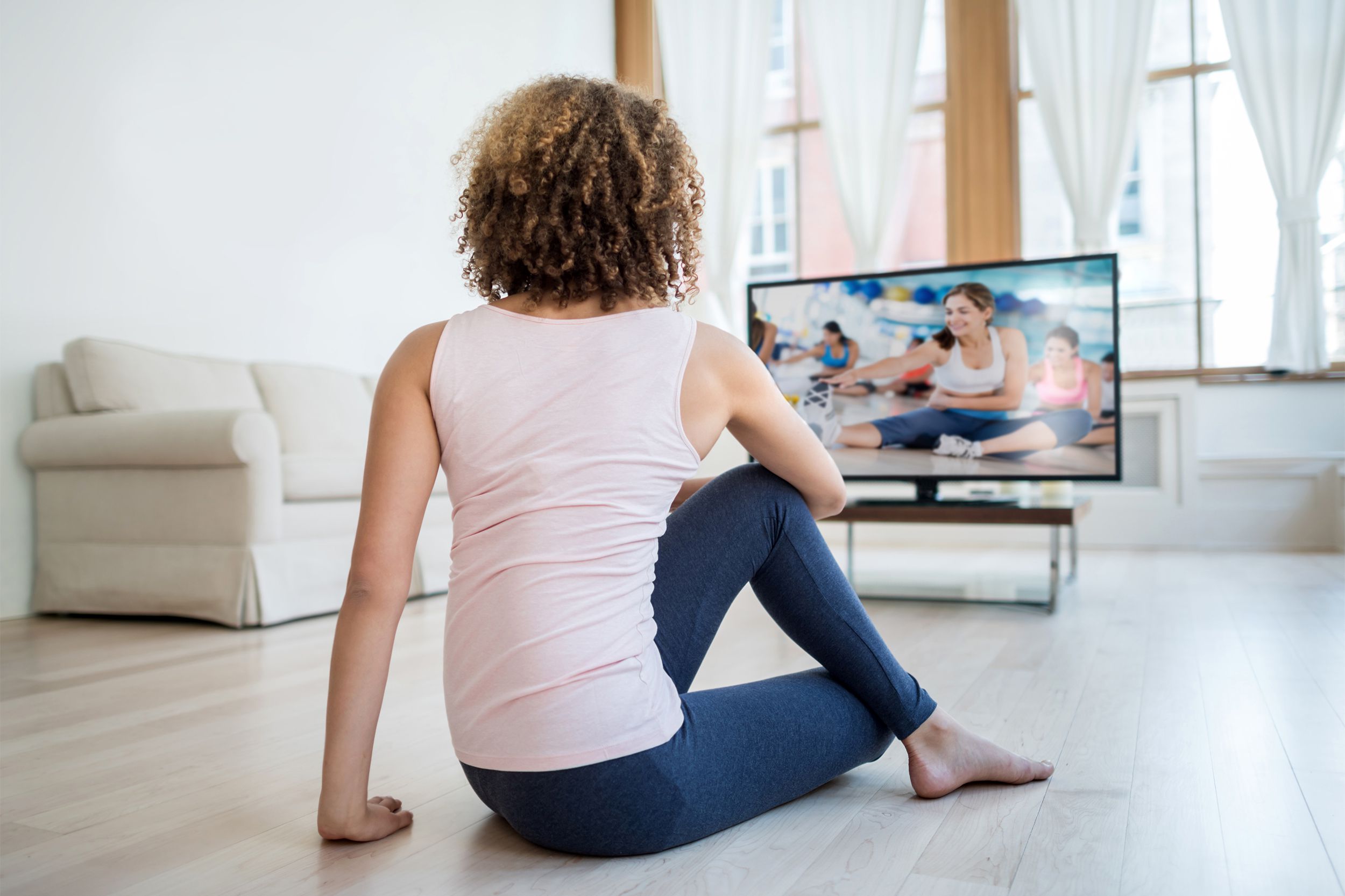 Woman stretching in front of TV watching a workout video