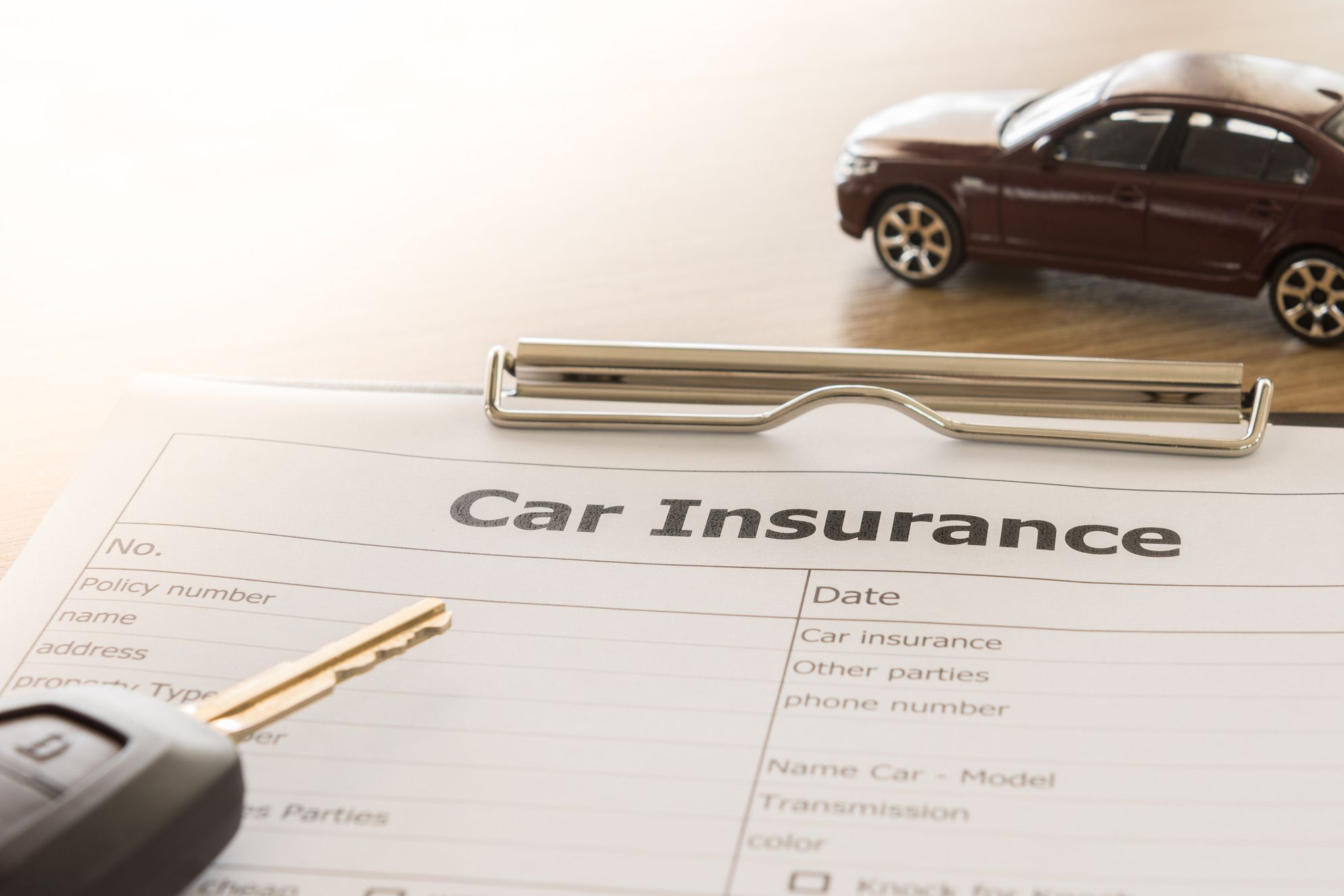 car insurance application form with car model and key remote on desk