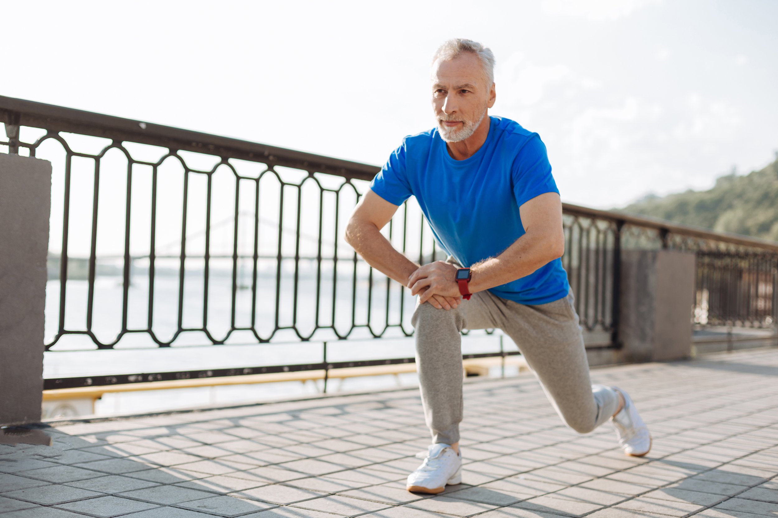 senior man doing lunges during morning run