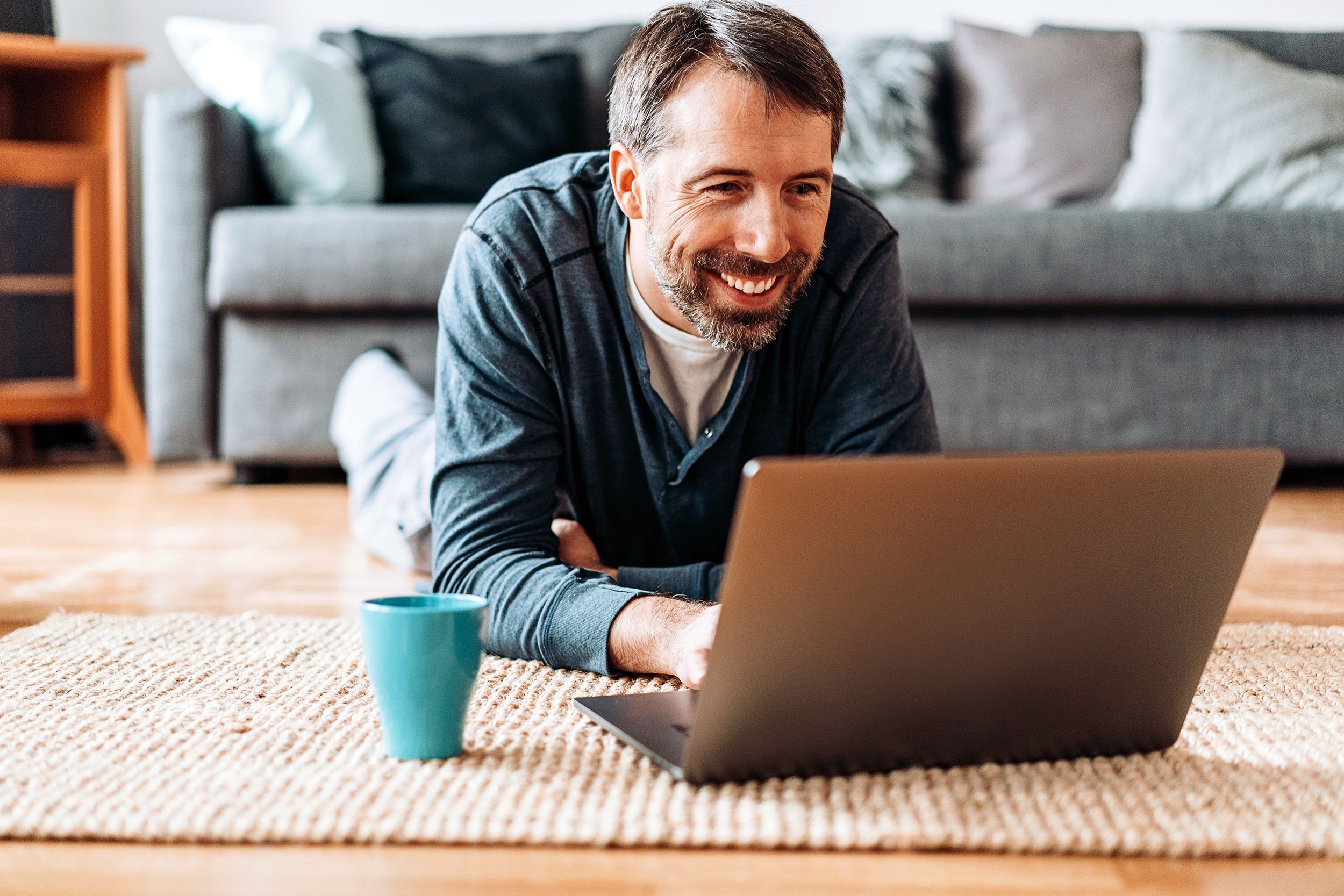middle-aged man laying on floor, working on laptop