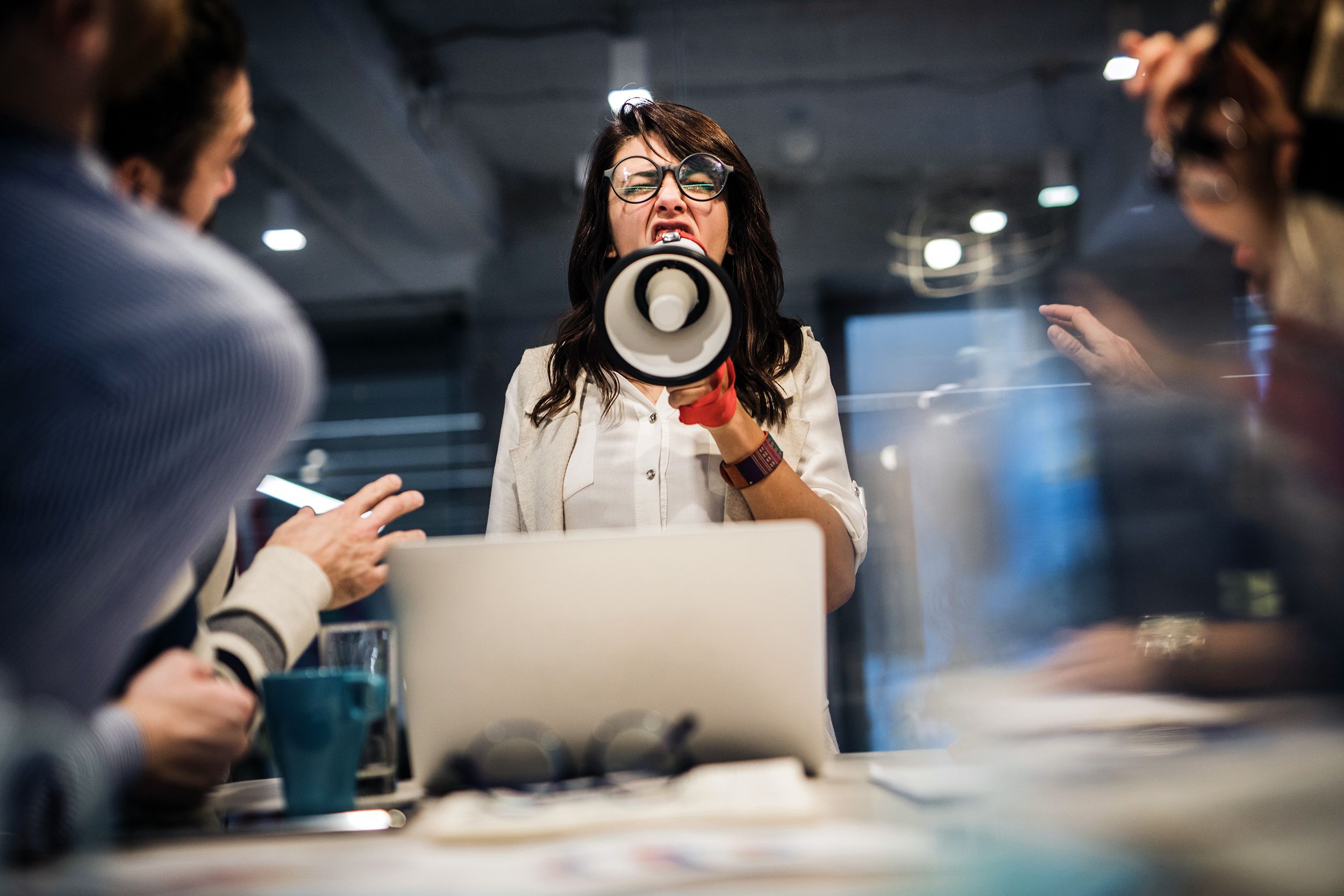 rude female leader yelling at her coworkers through megaphone in the office