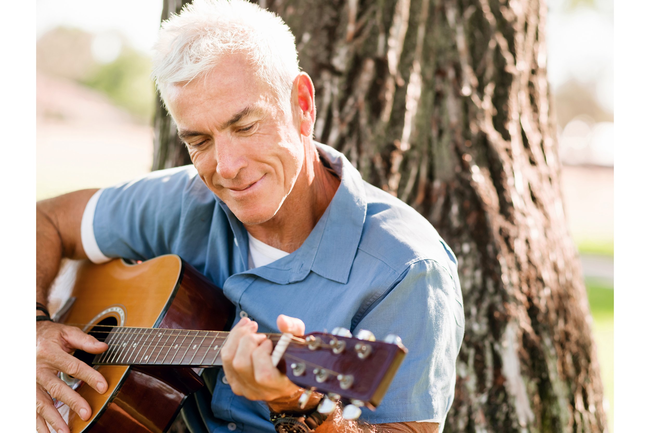 Senior man playing guitar outside