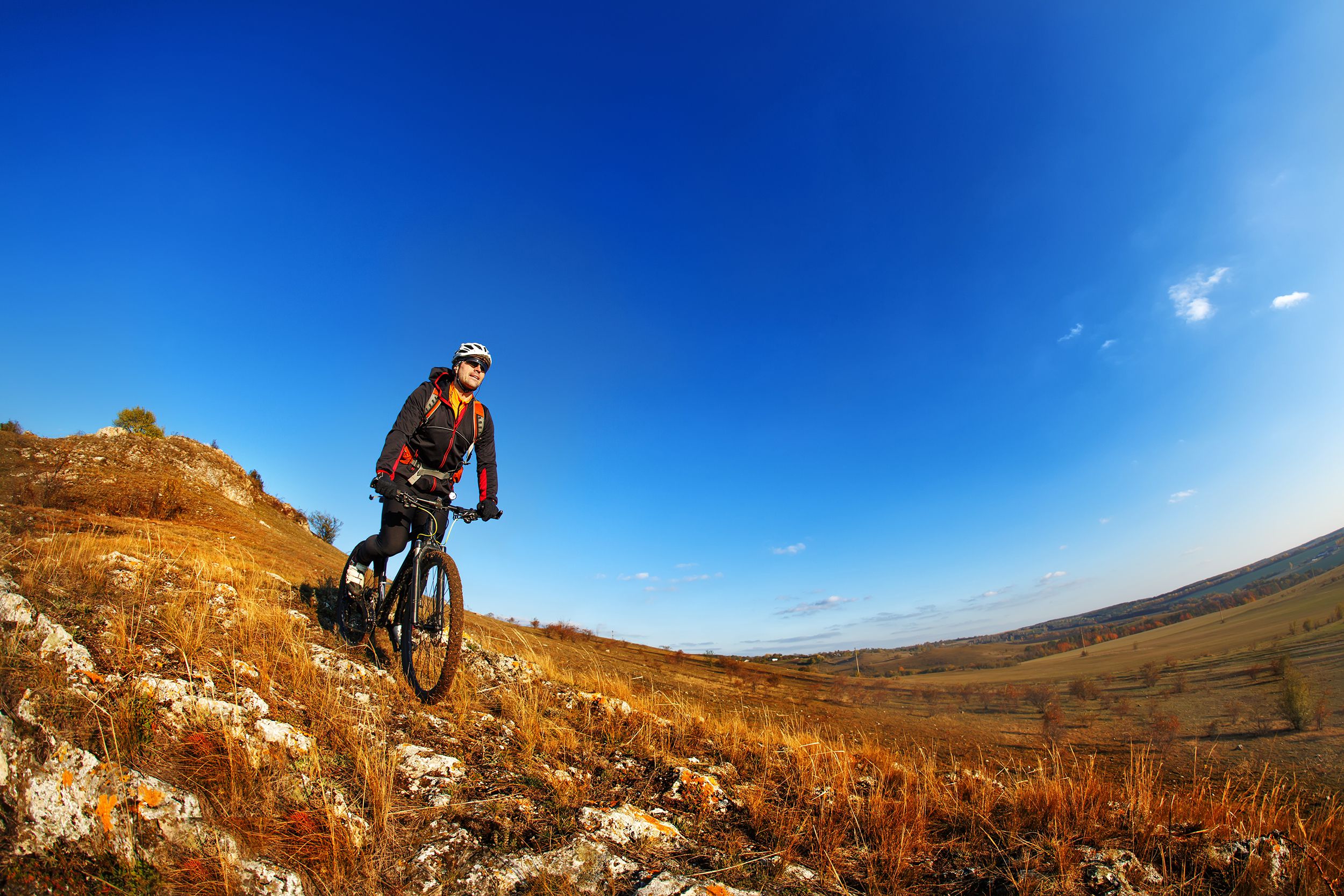 wide angle view of a cyclist riding a bike on a nature trail in the mountains