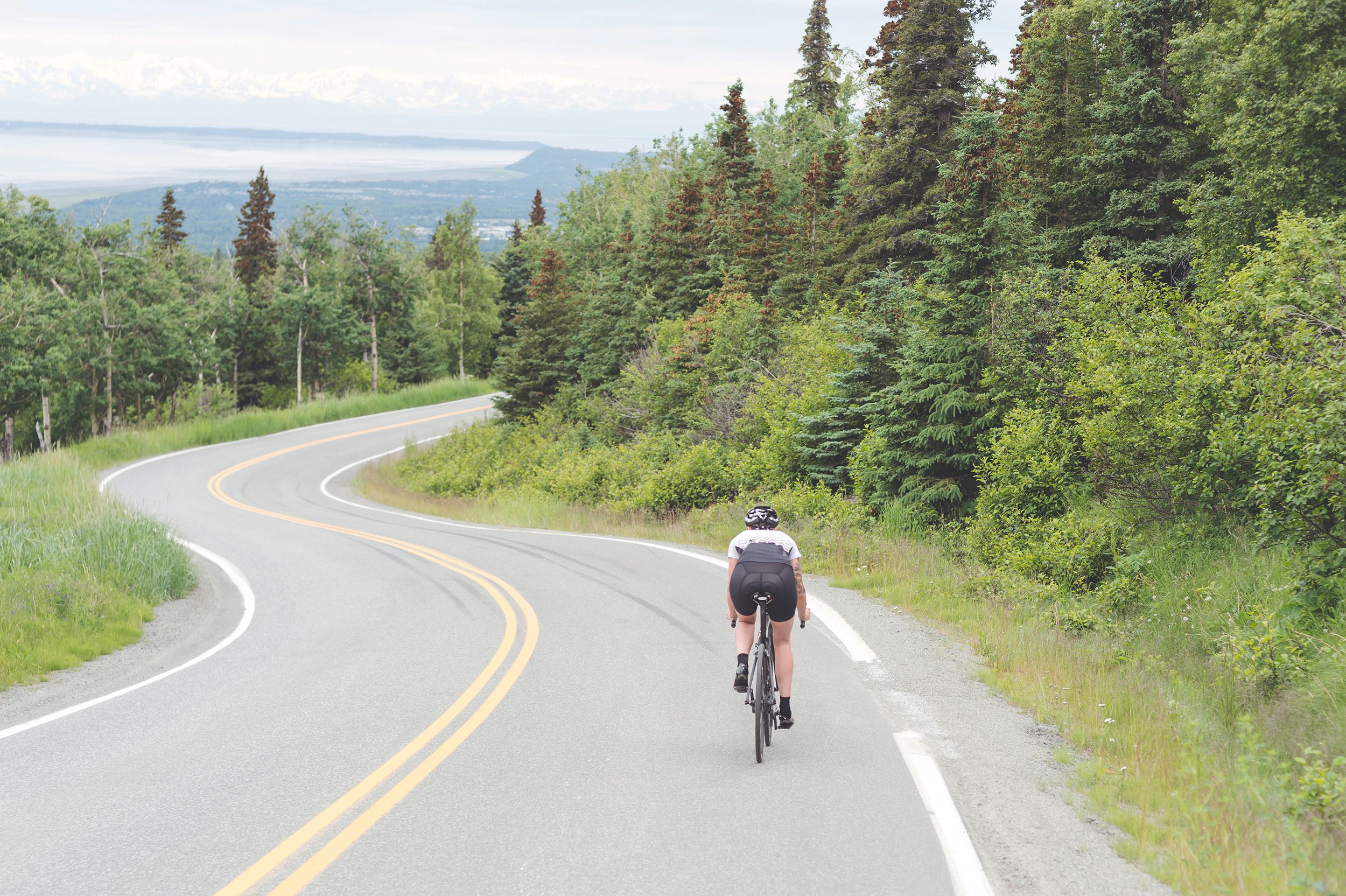 female cyclist cruises along a rural highway on a dry and moderate morning, Alaska