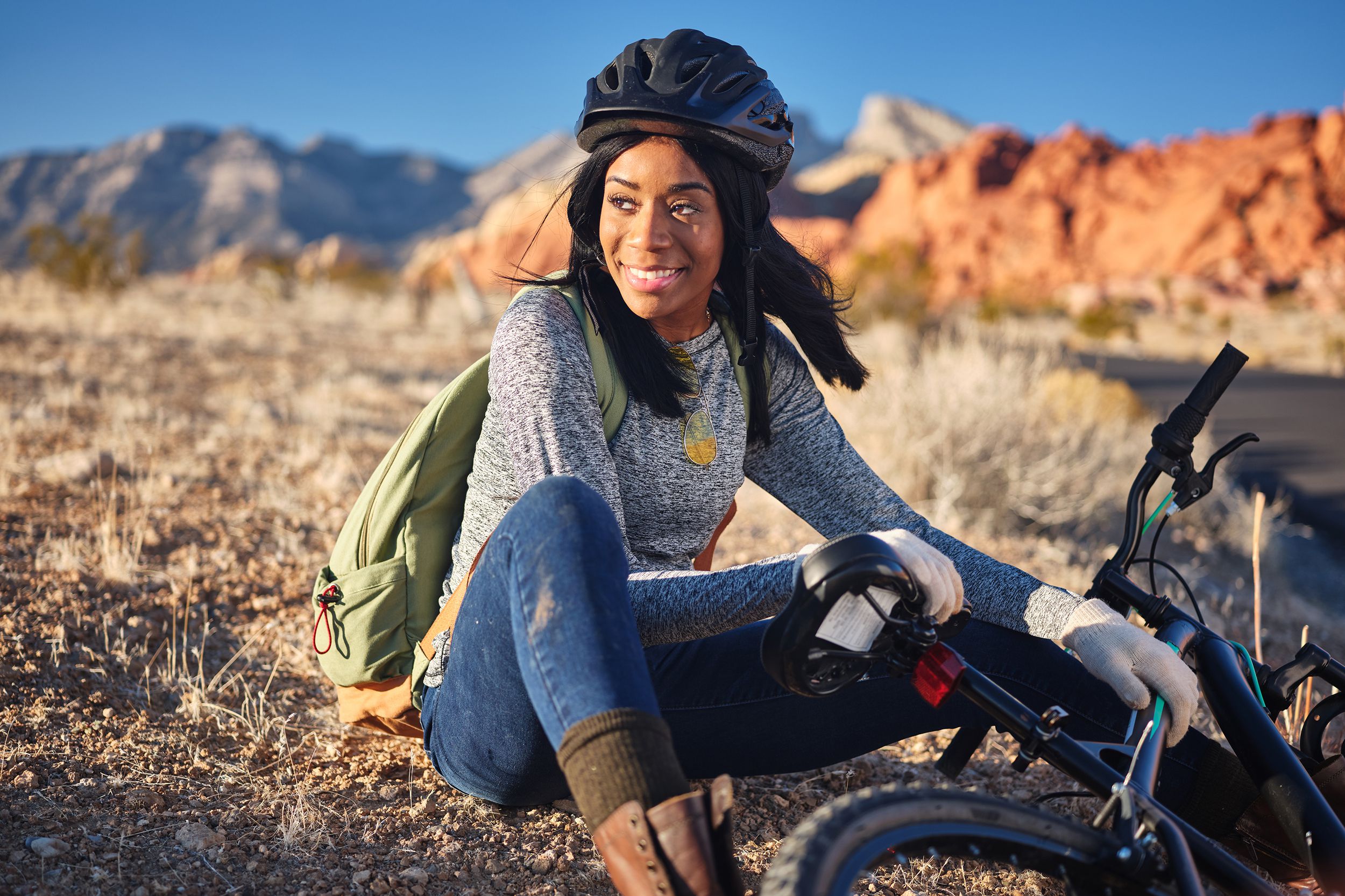 african american woman stopping to take a rest beside bike during the day