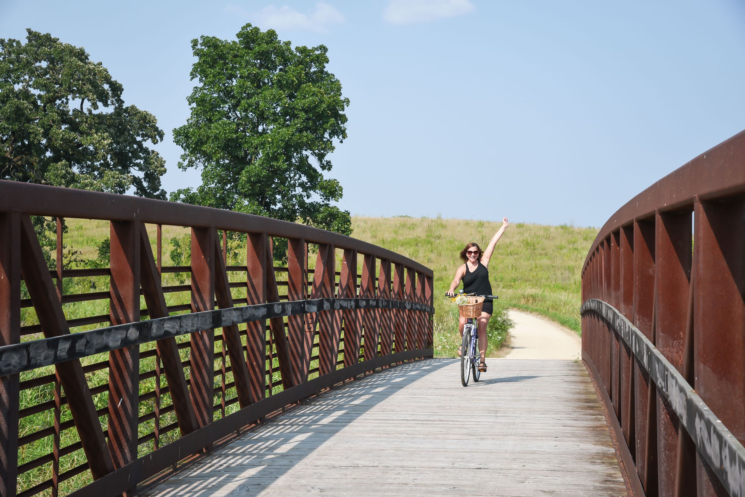 woman riding on bike path with basket of flowers on handlebars, Wisconsin