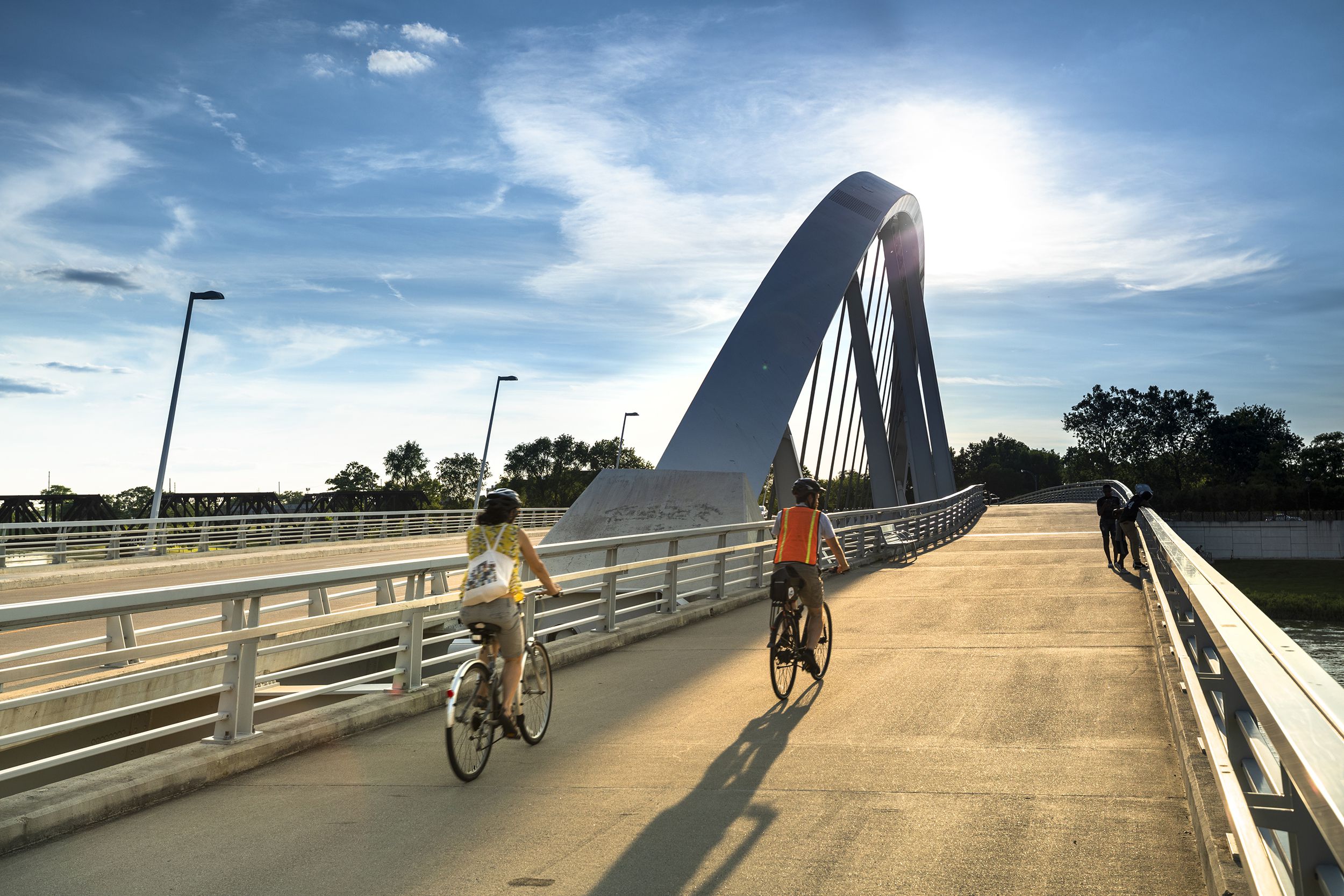two people ride bicycles on the Rich Street Bridge over the Scioto River along the Riverfront Park, Columbus, Ohio