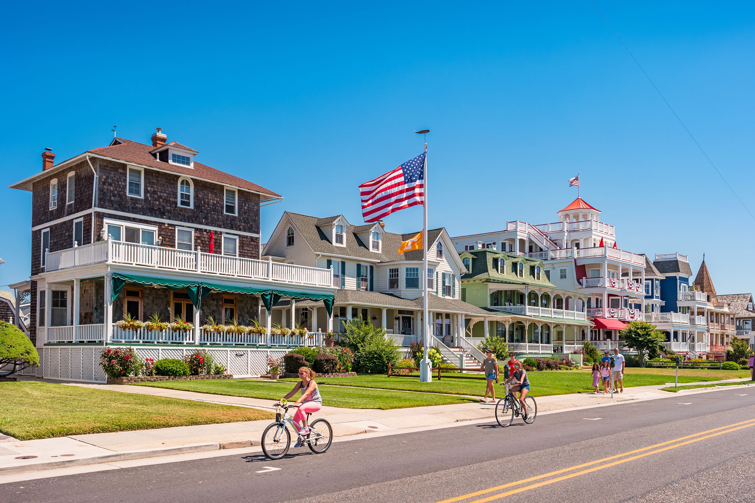 people bike and walk in front of traditional villas in Cape May, New Jersey