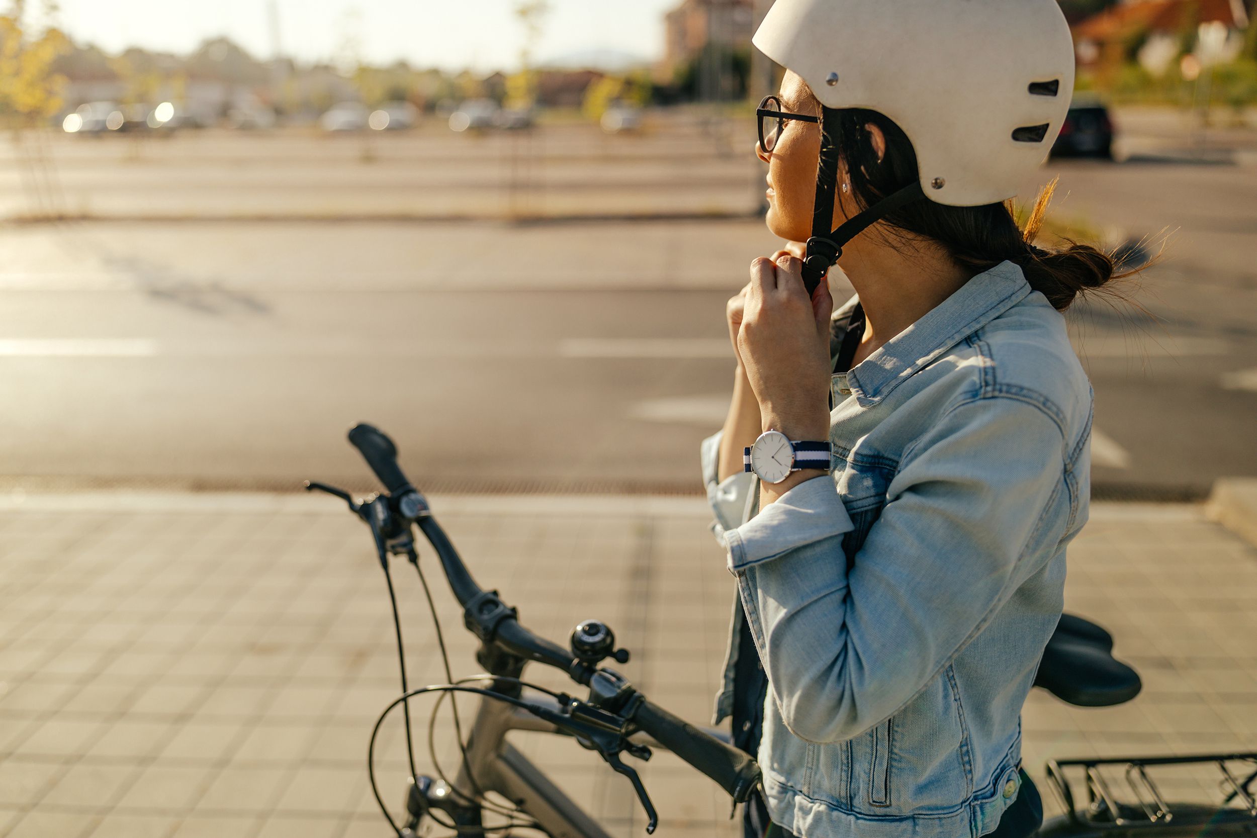 young woman putting her helmet, preparing for the bike ride