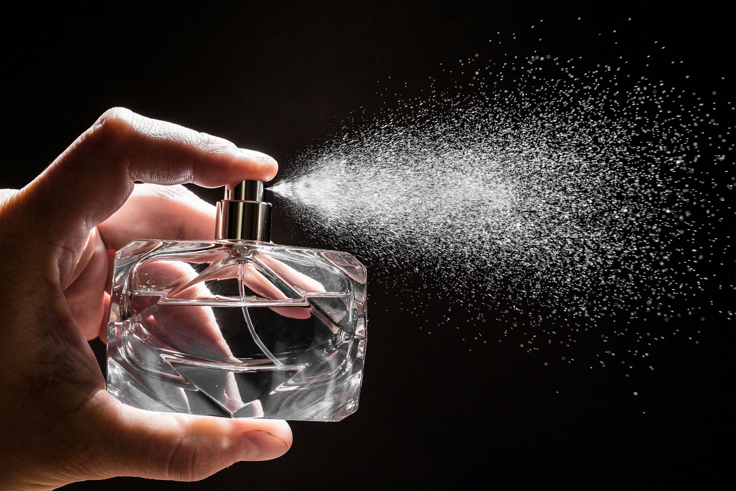 spraying perfume on dark background