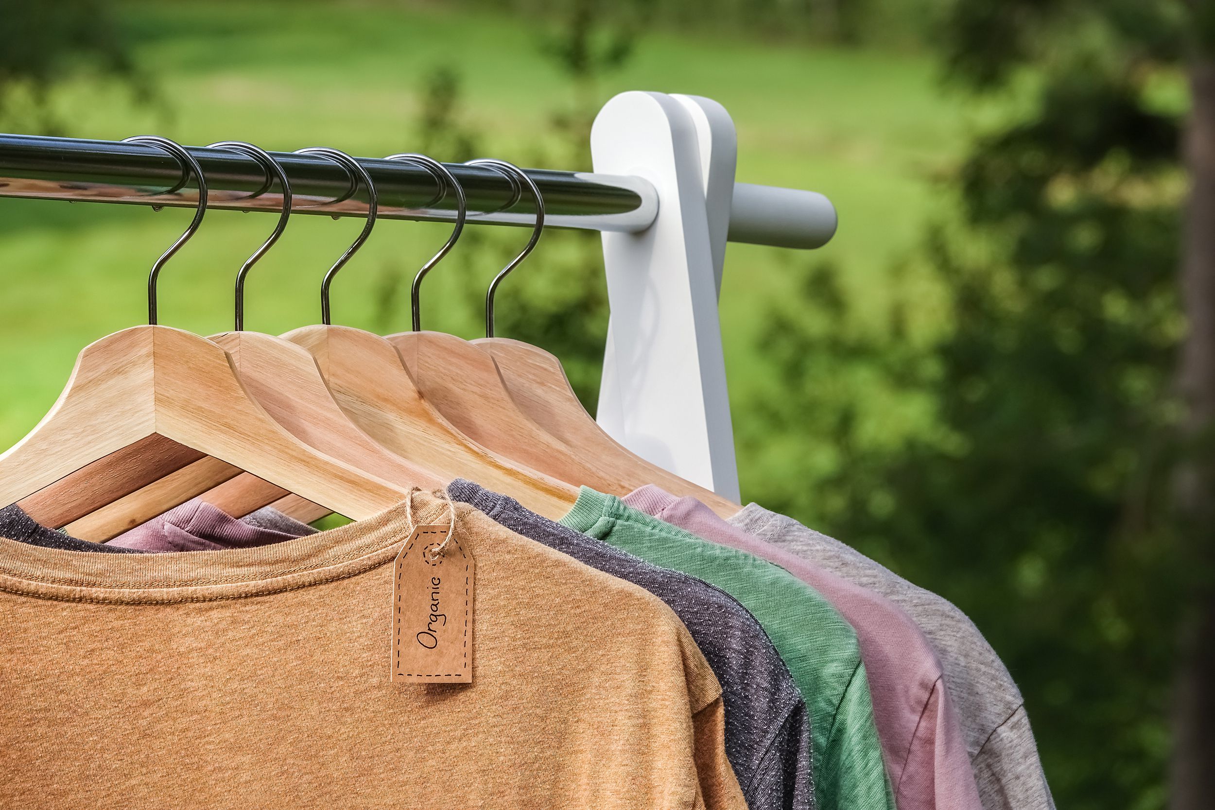 organic clothes t-shirts hanging on wooden hangers in a row