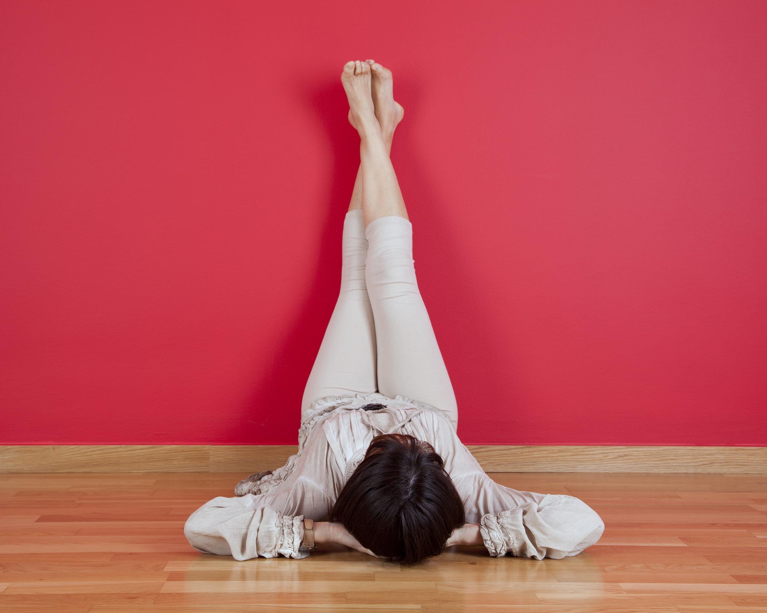 woman laying on the floor of her house next to a red wall