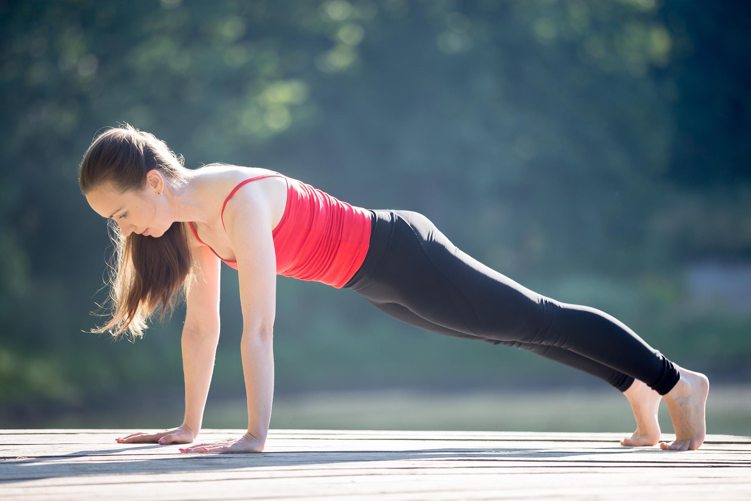 woman doing plank on yoga mat outside