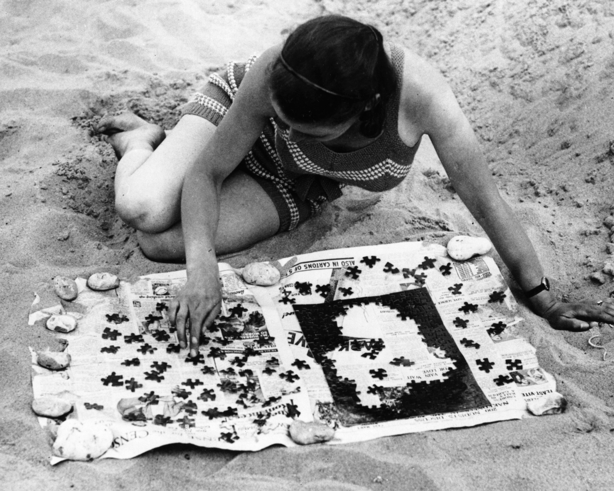 girl in the 1930's doing a jigsaw puzzle on the beach