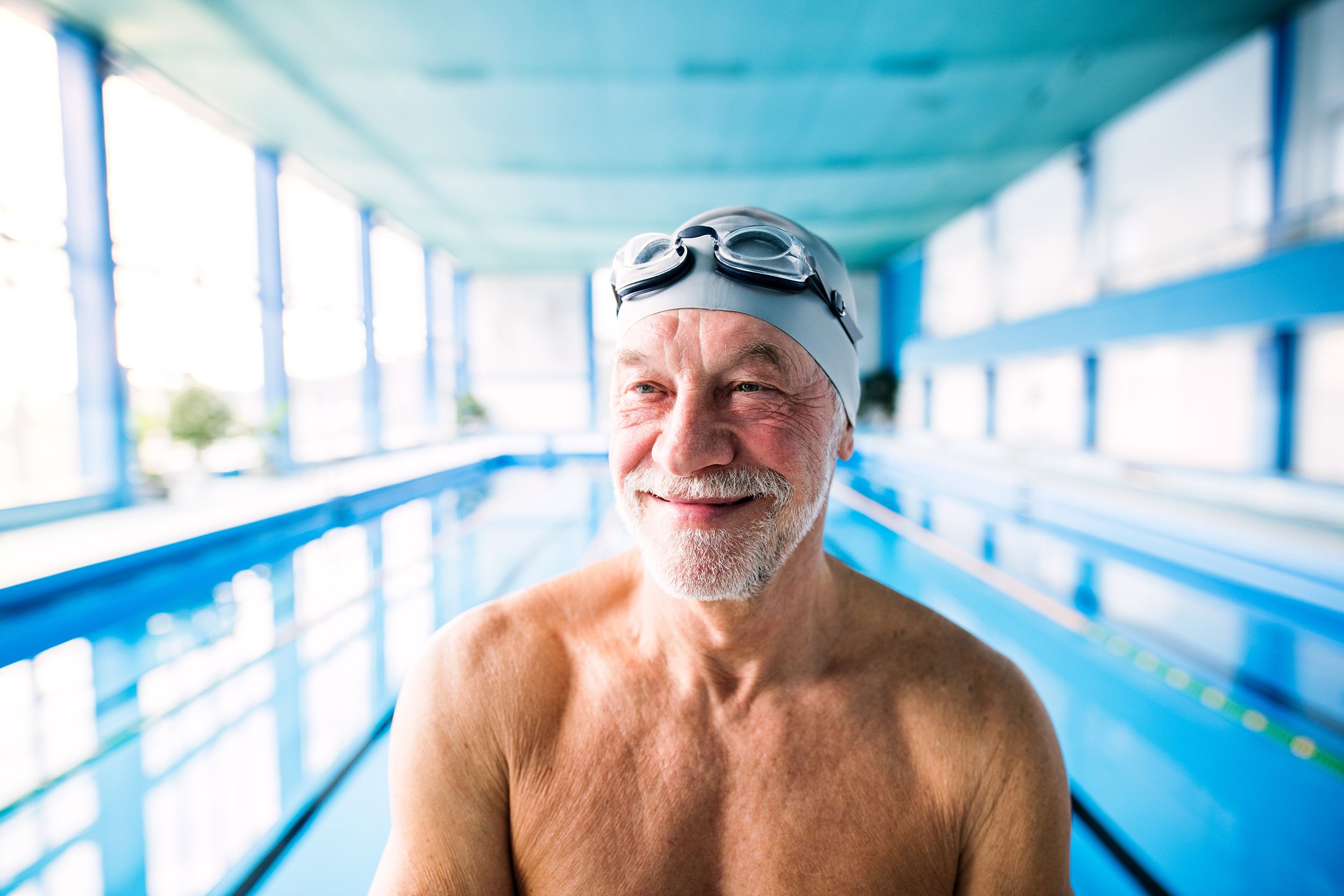 Senior man standing in front of an indoor pool