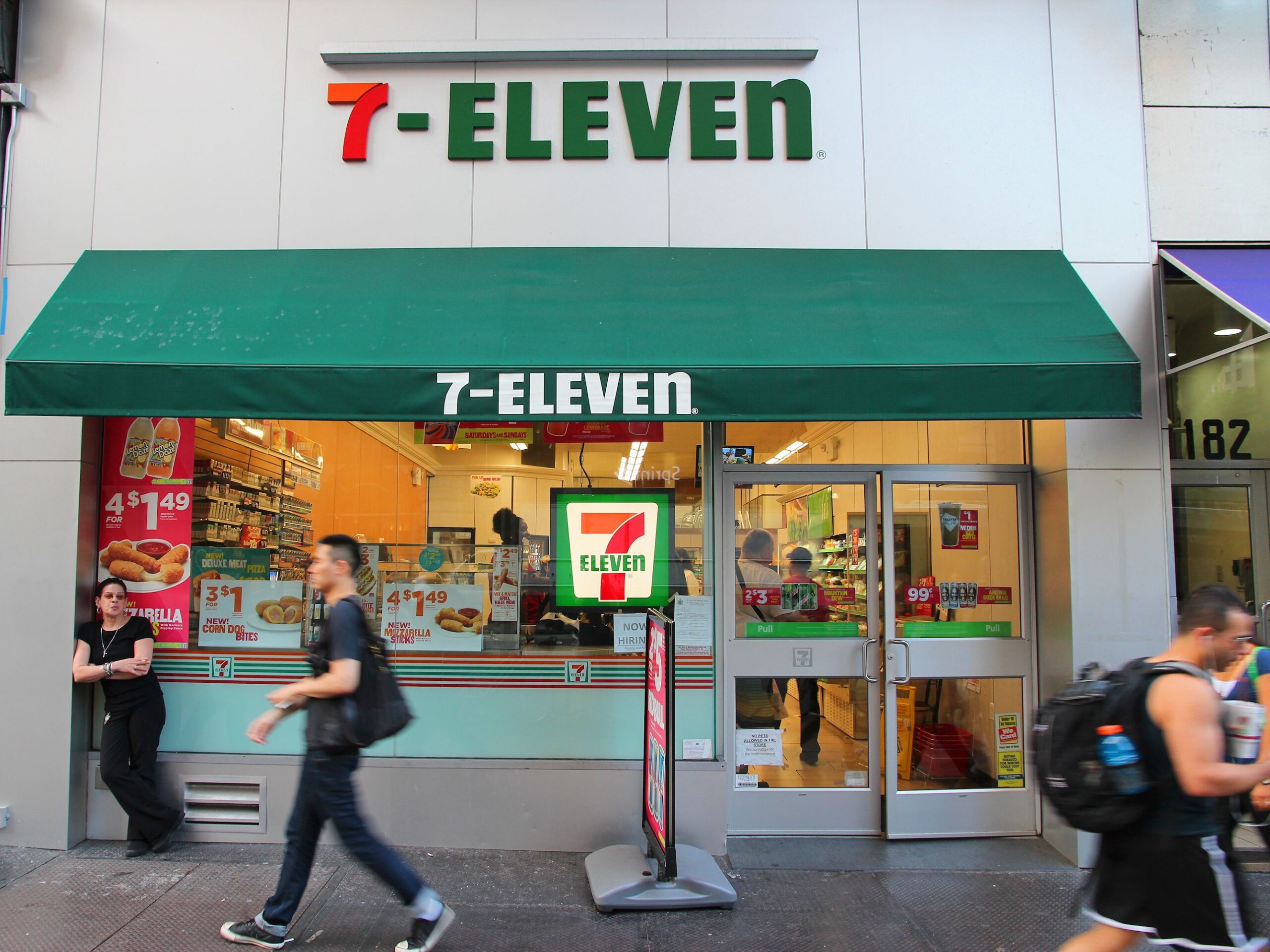People walk past 7-Eleven convenience store in New York