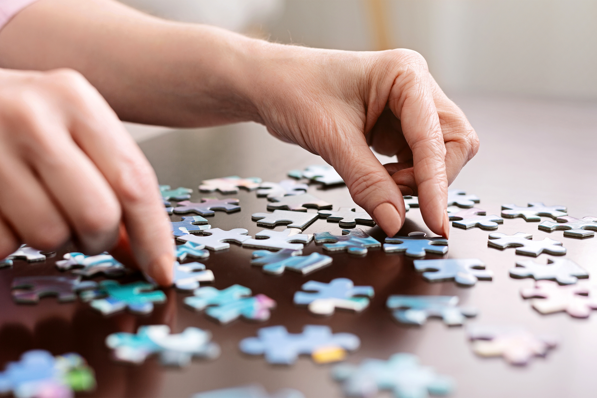 closeup of hands putting together a jigsaw puzzle