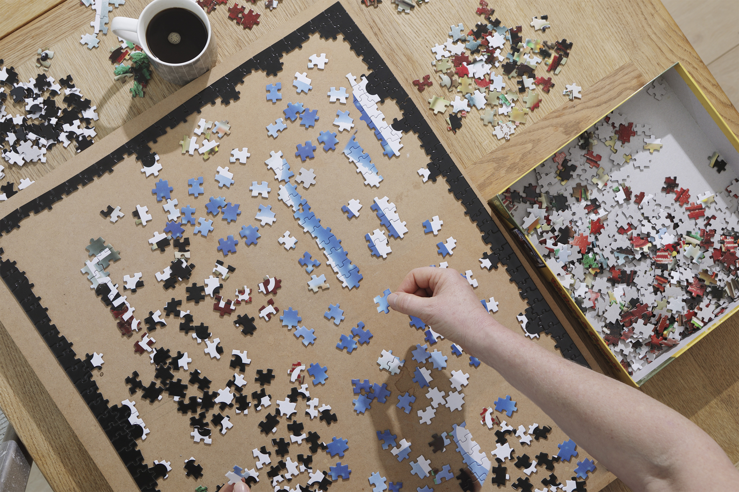 hands doing a large puzzle with a cup of coffee