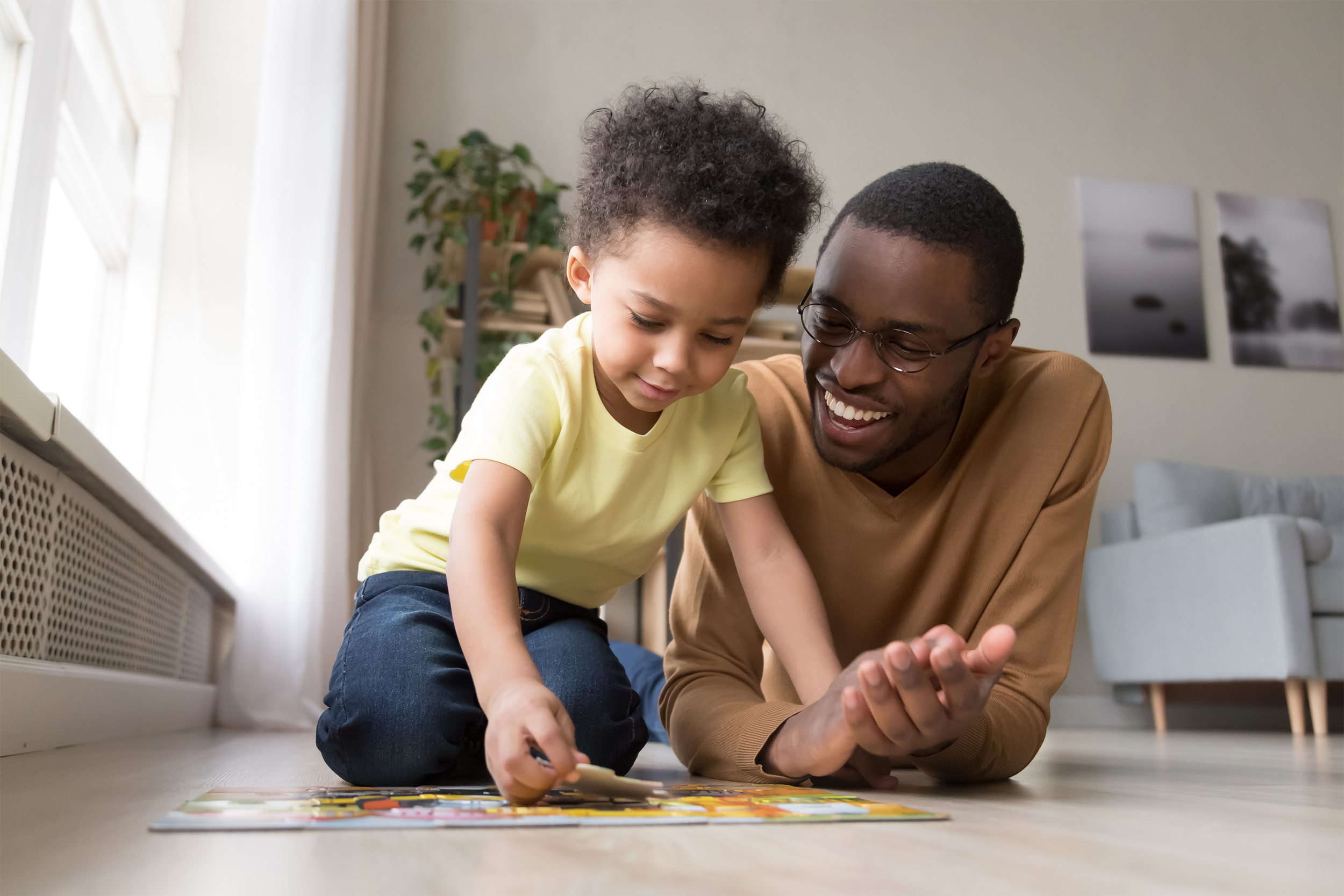 father and son doing a puzzle on the floor at home