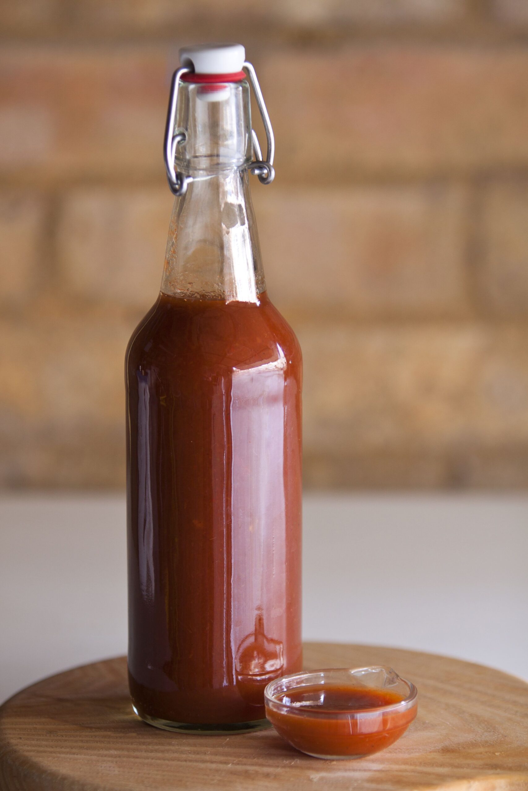 hot sauce in bottle and tiny bowl on wooden bench