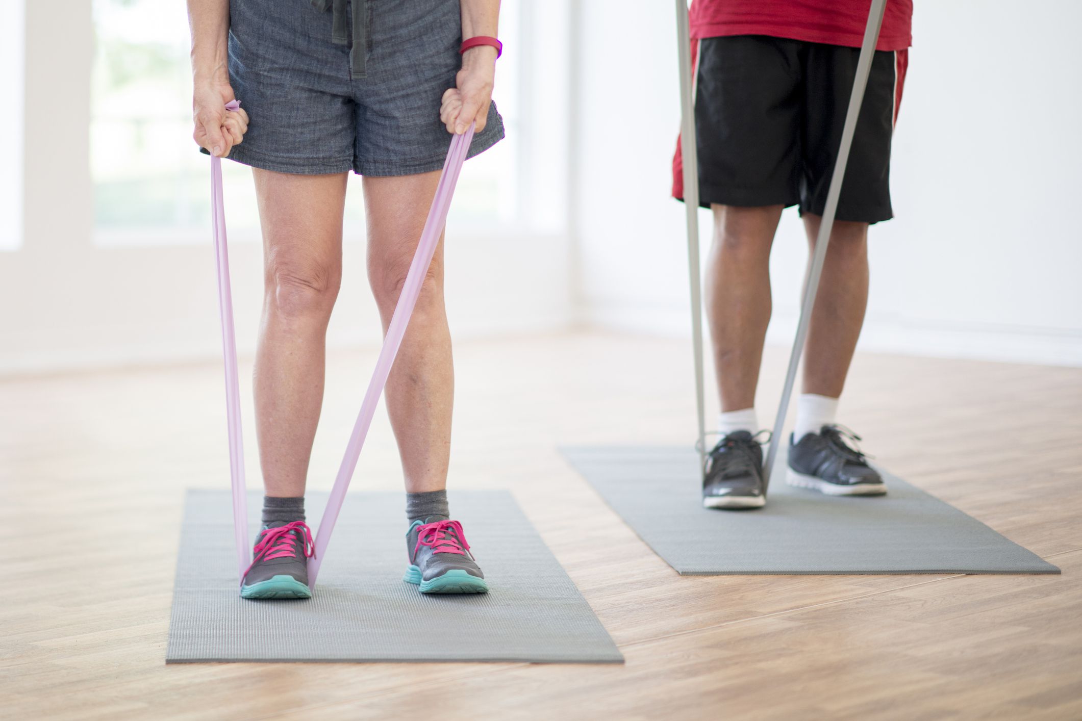 A senior adult couple are using resistance bands during their workout at the gym.