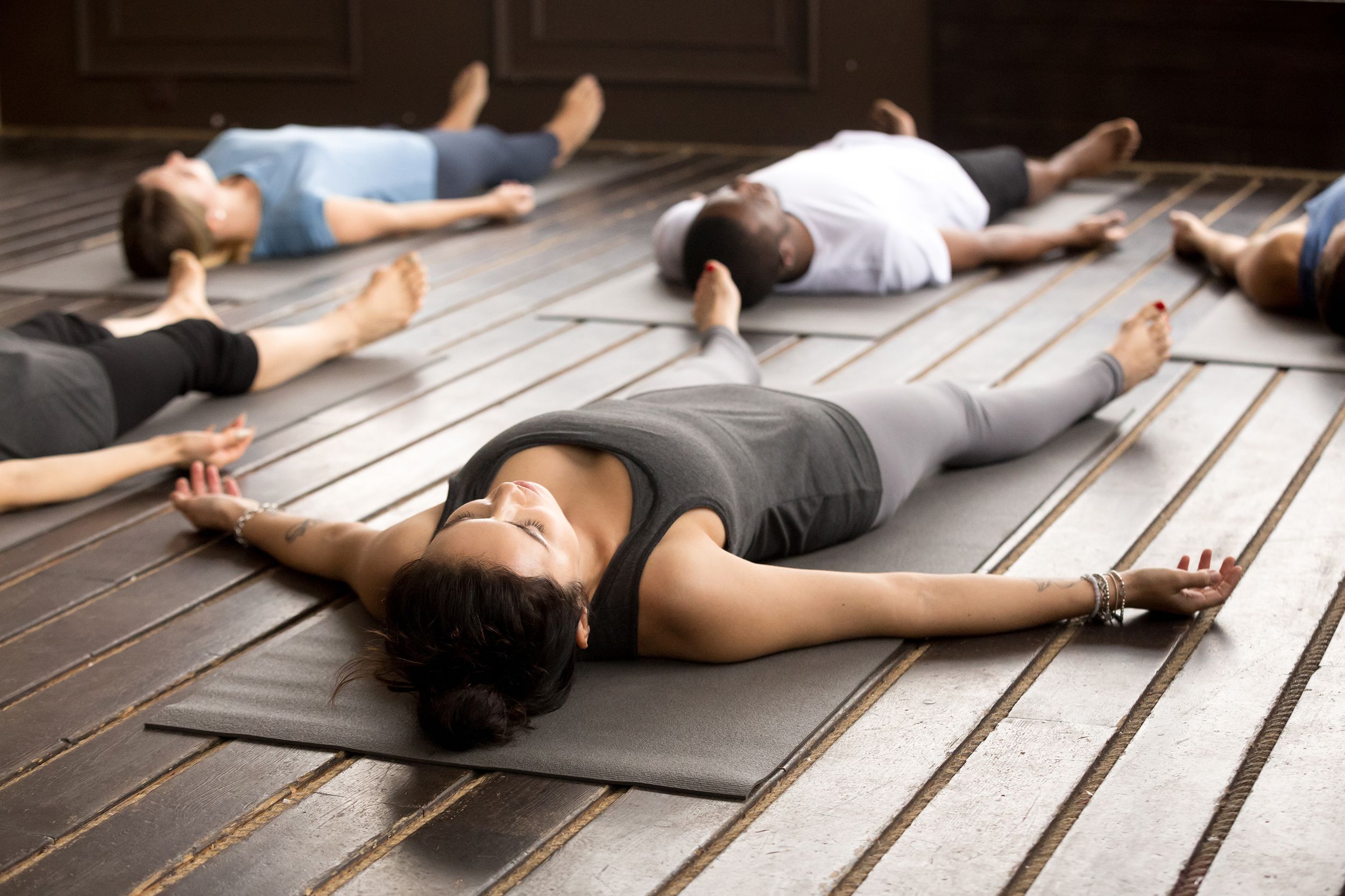 group of people doing corpse pose in yoga studio