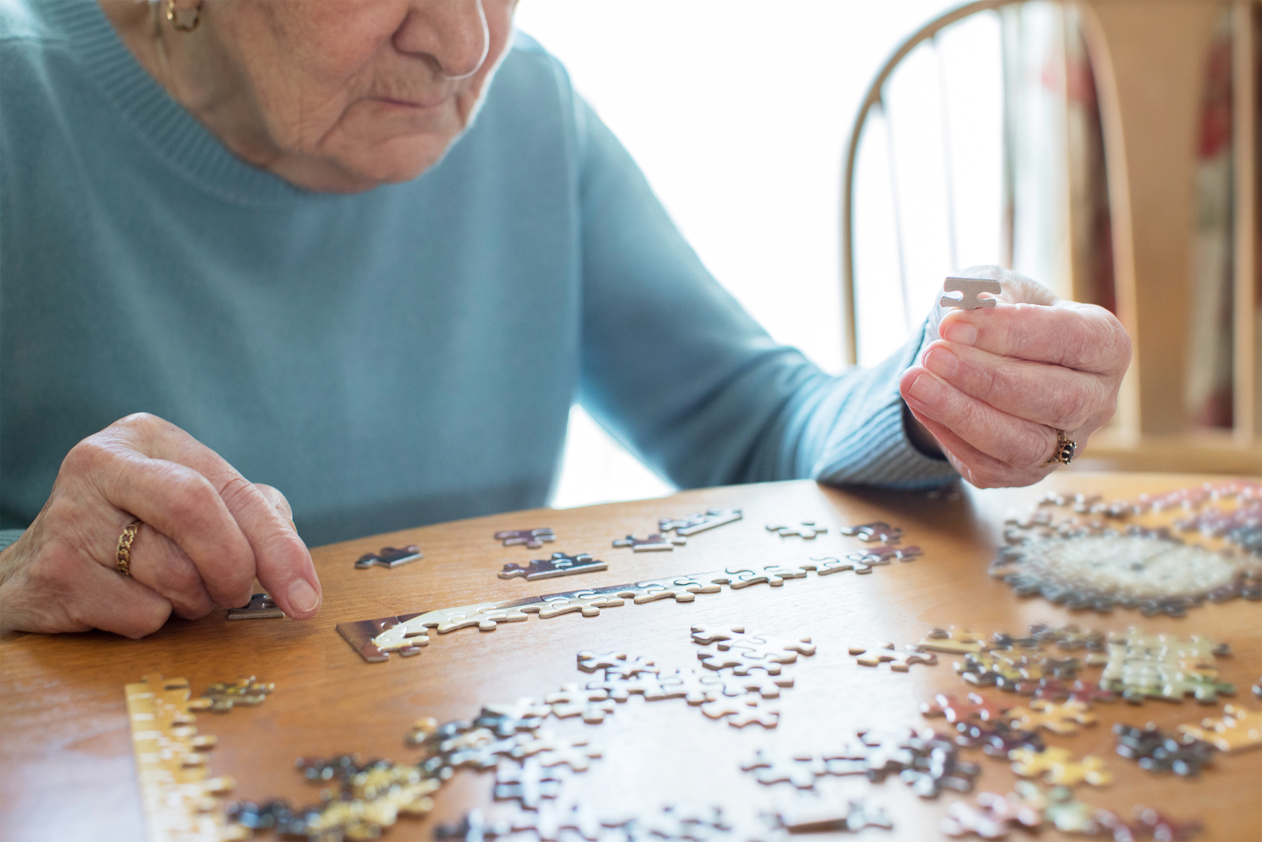 elderly woman doing a puzzle at her table