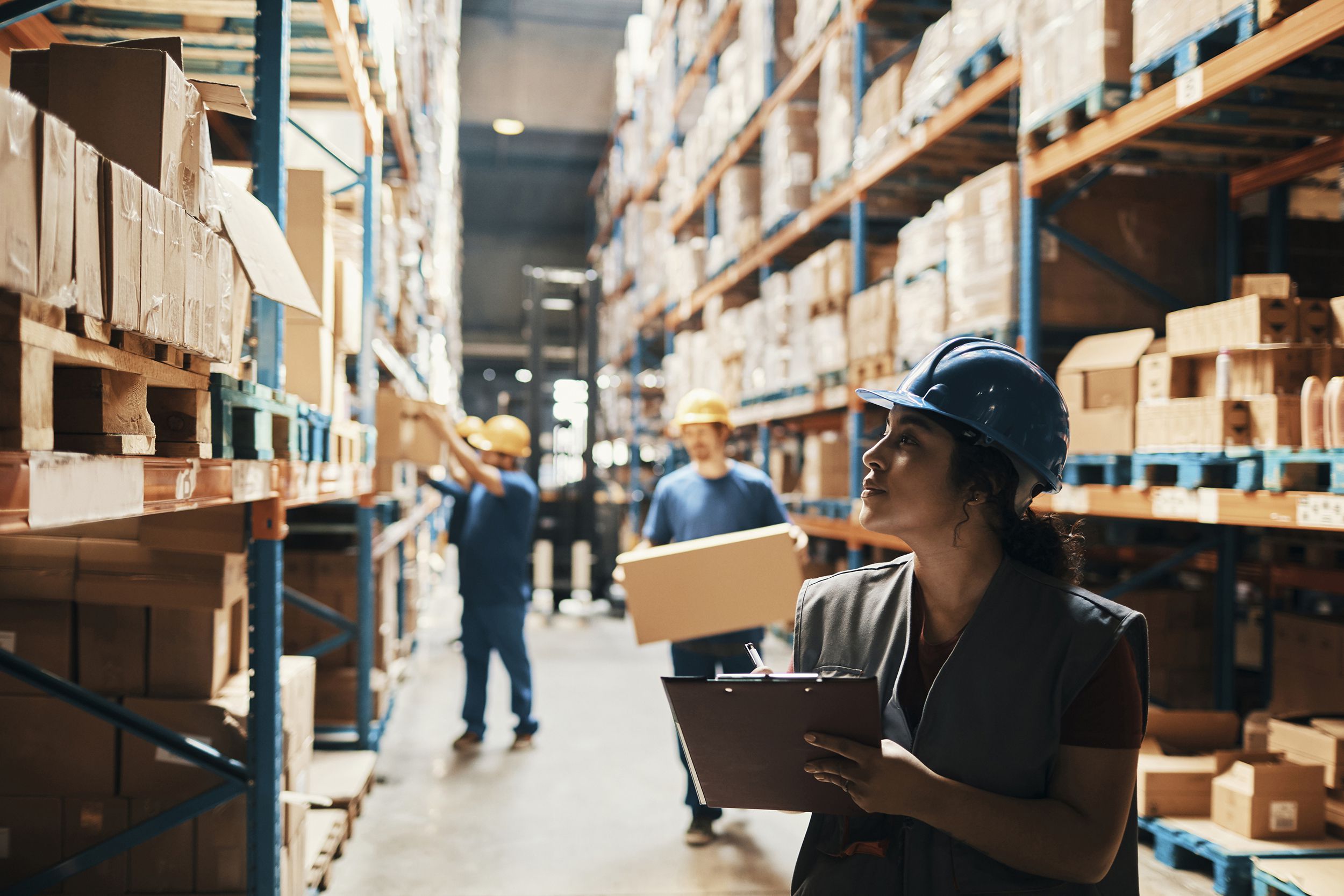 warehouse workers in warehouse, one with clipboard