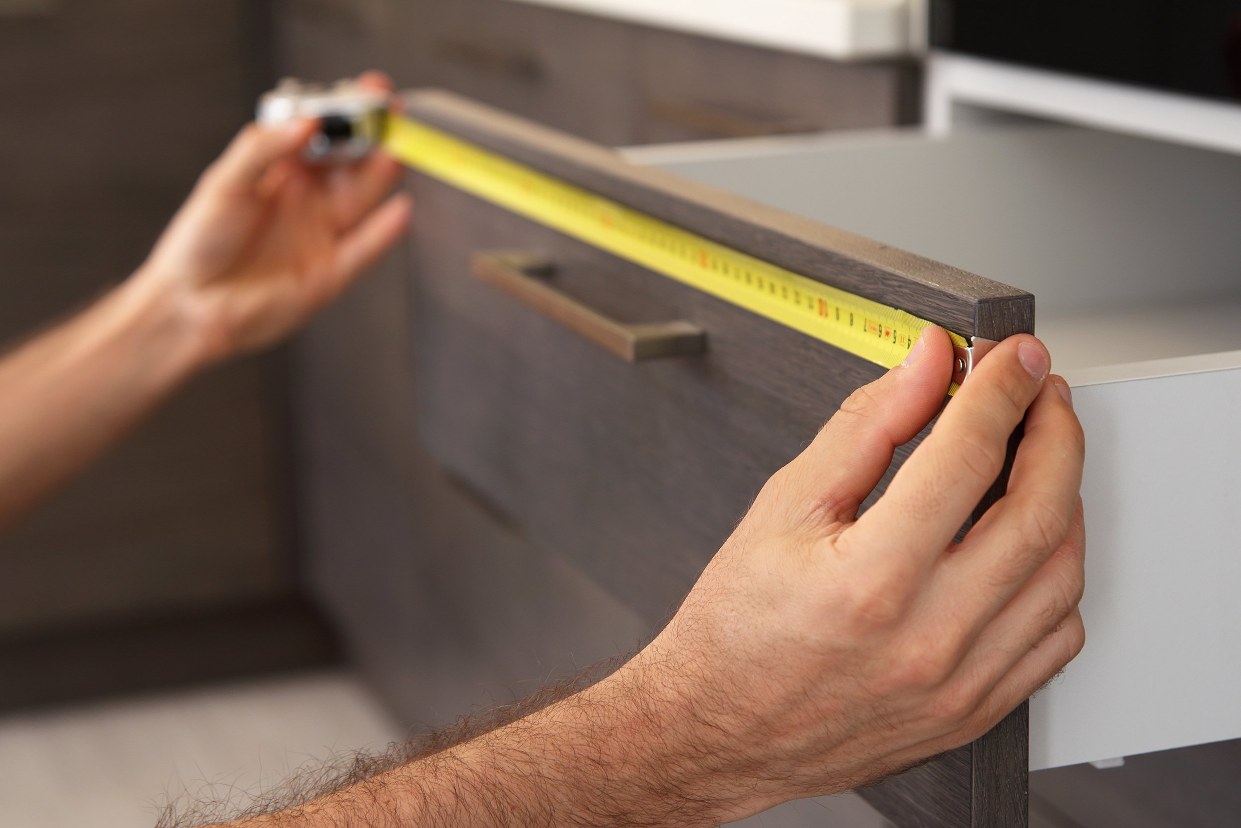 hands measuring kitchen cabinet
