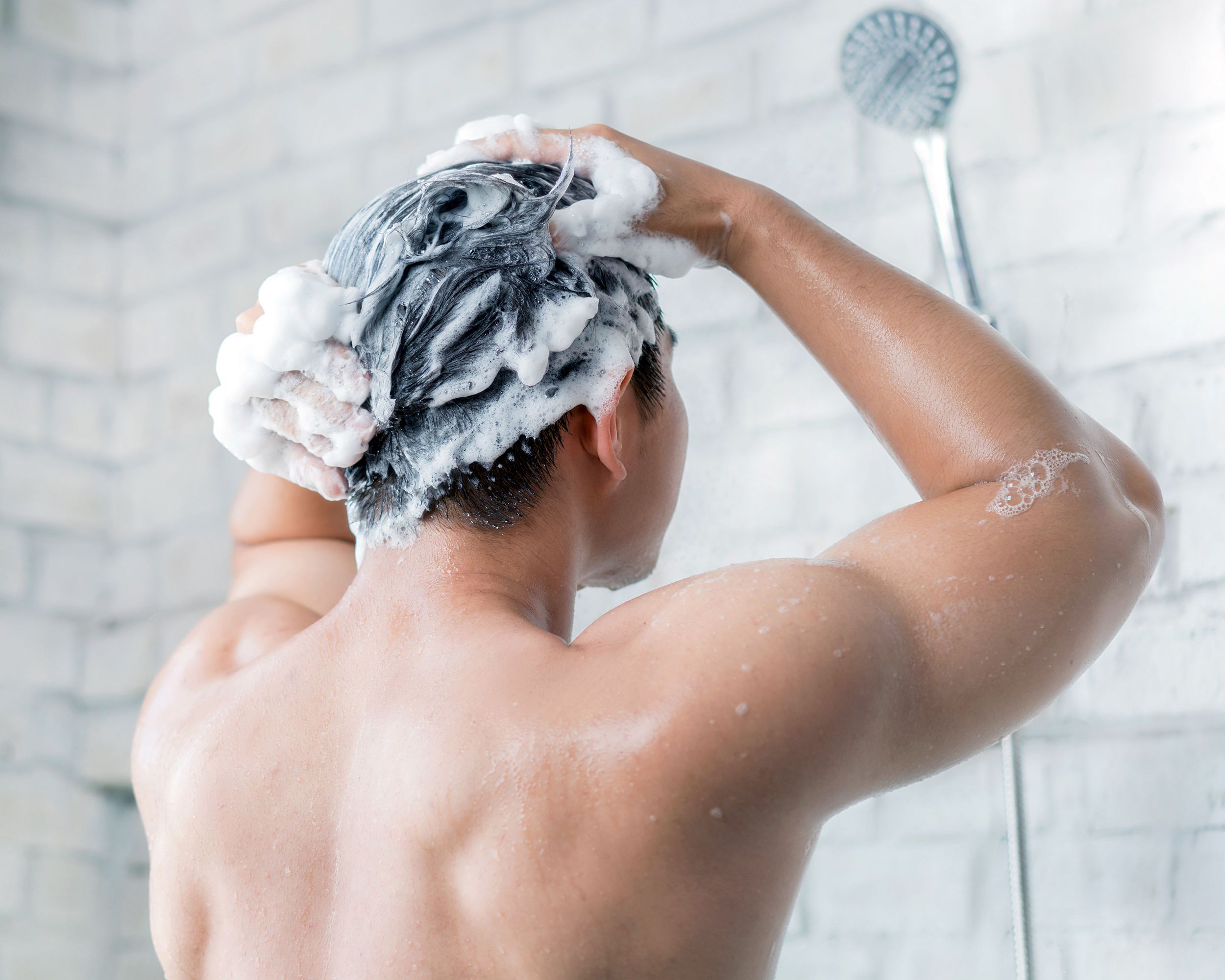 Asian man washing hair in shower