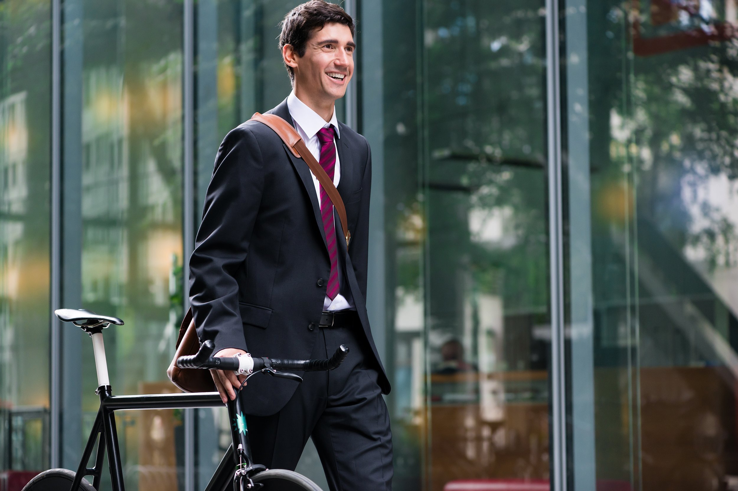 happy active young man wearing business suit while walking to the job after bicycle commuting