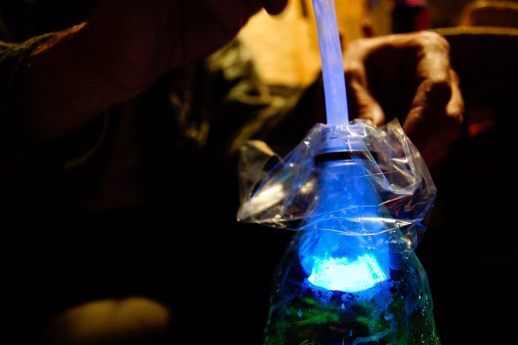 hands putting glow stick in bottle