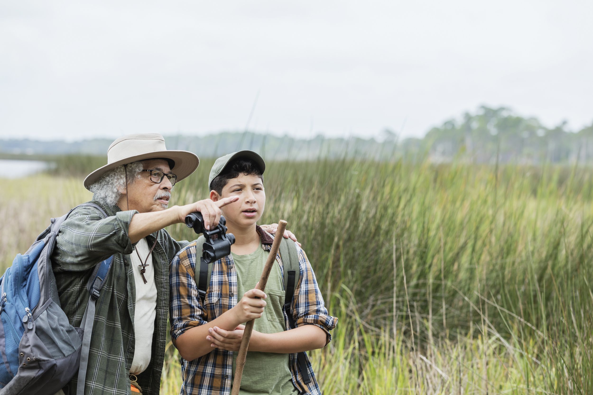 hispanic boy hiking with grandfather, bird watching