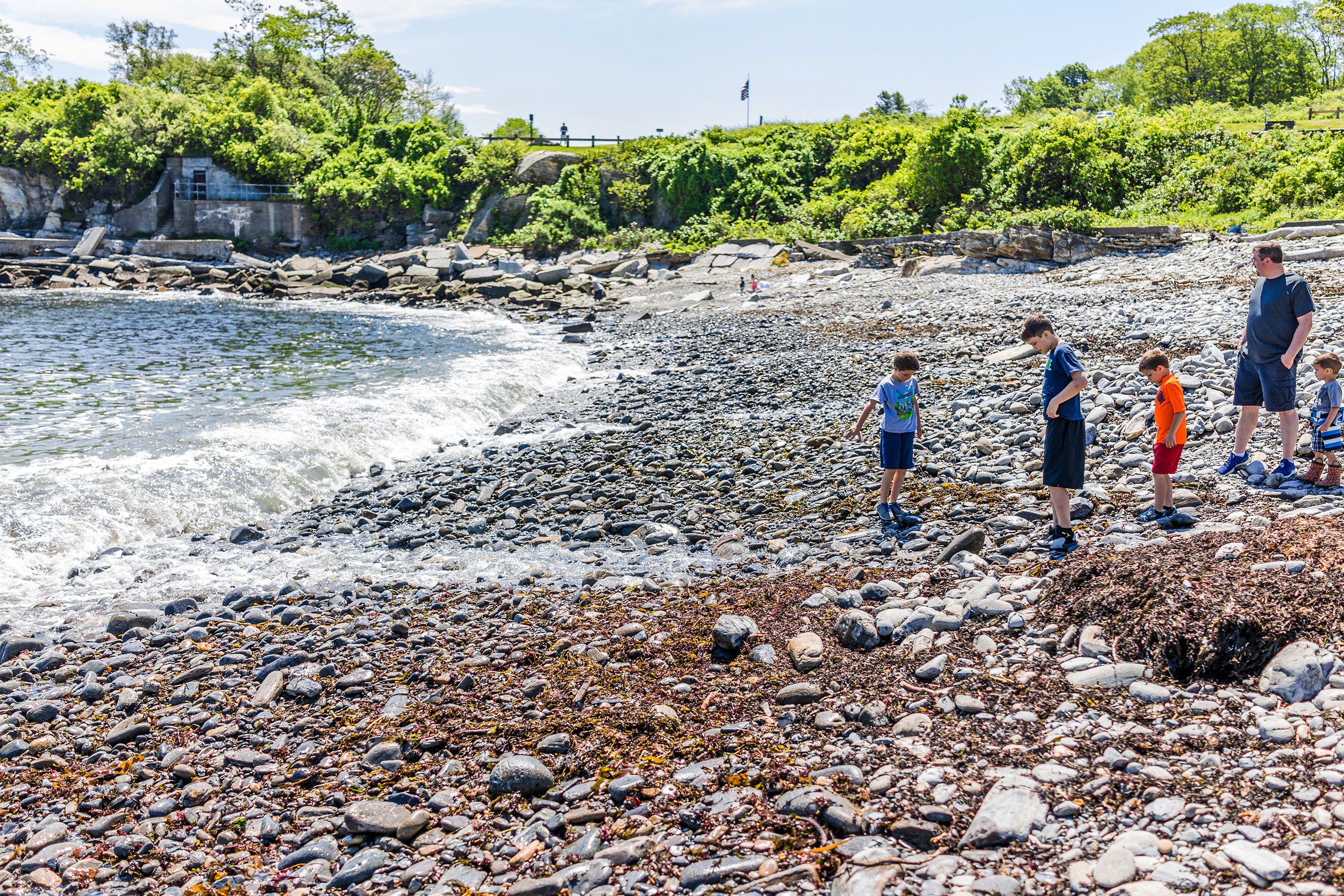 family with children on rocky public beach called Ship Cove by Portland Head Lighthouse in Maine
