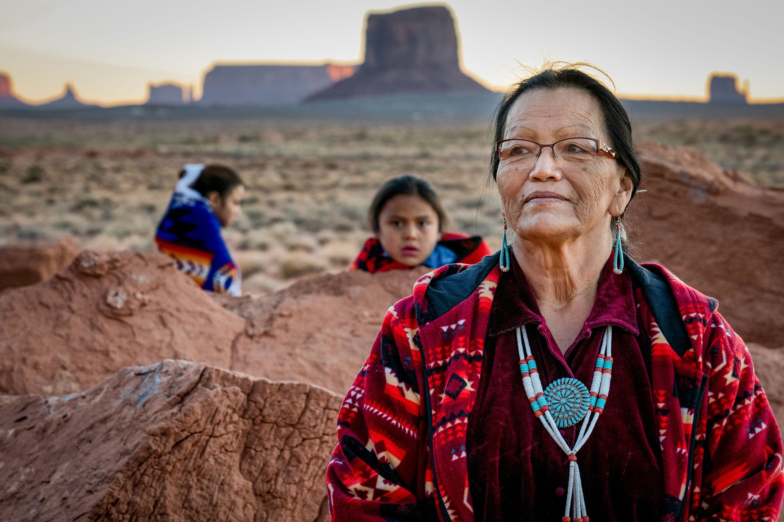 traditional Navajo grandmother with her grandson and granddaughter in front of the famous rock formations of the Monument Valley Tribal Park in Northern Arizona