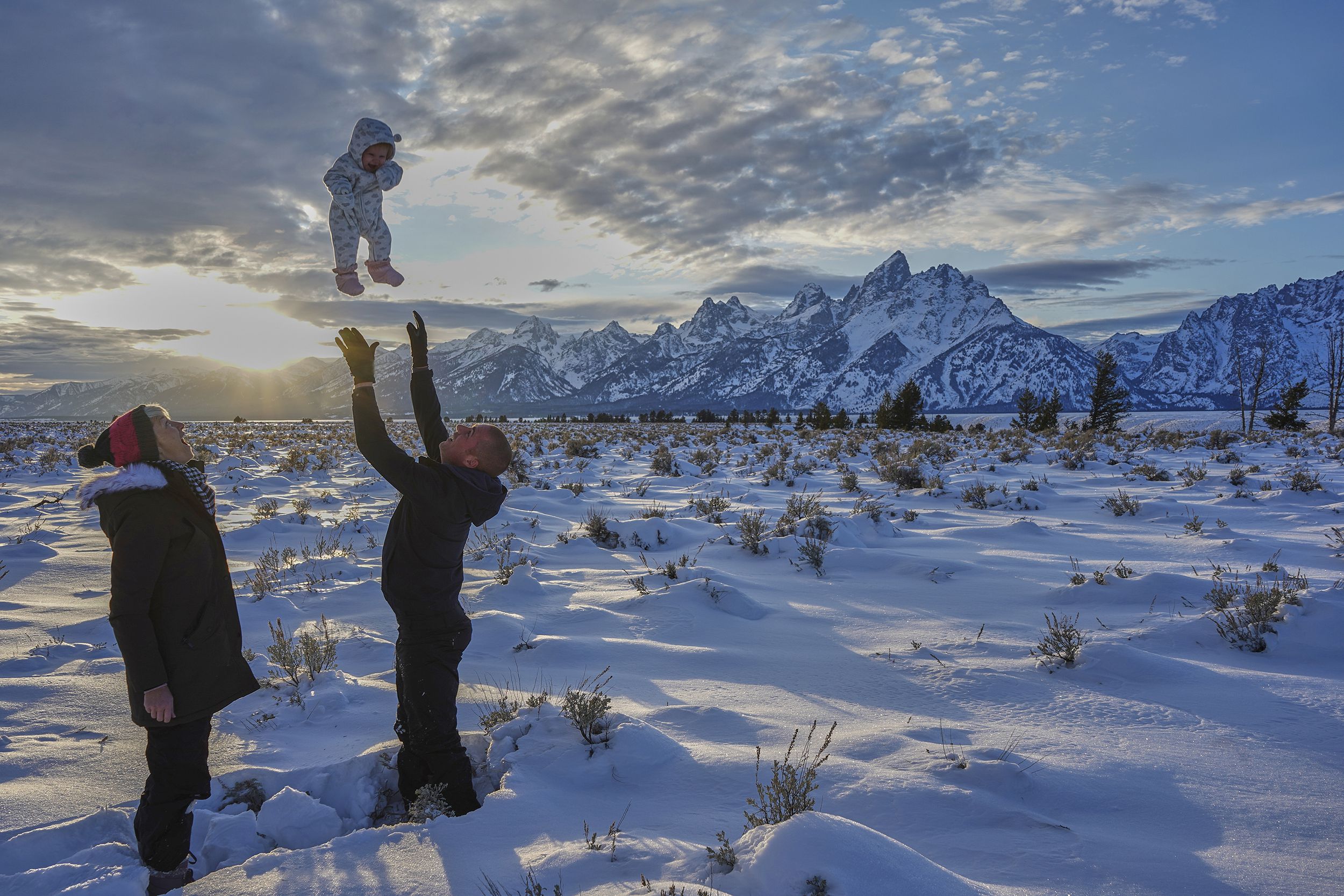 family playing in the snow at sunset in the winter at Christmas time in the Grand Tetons National Park