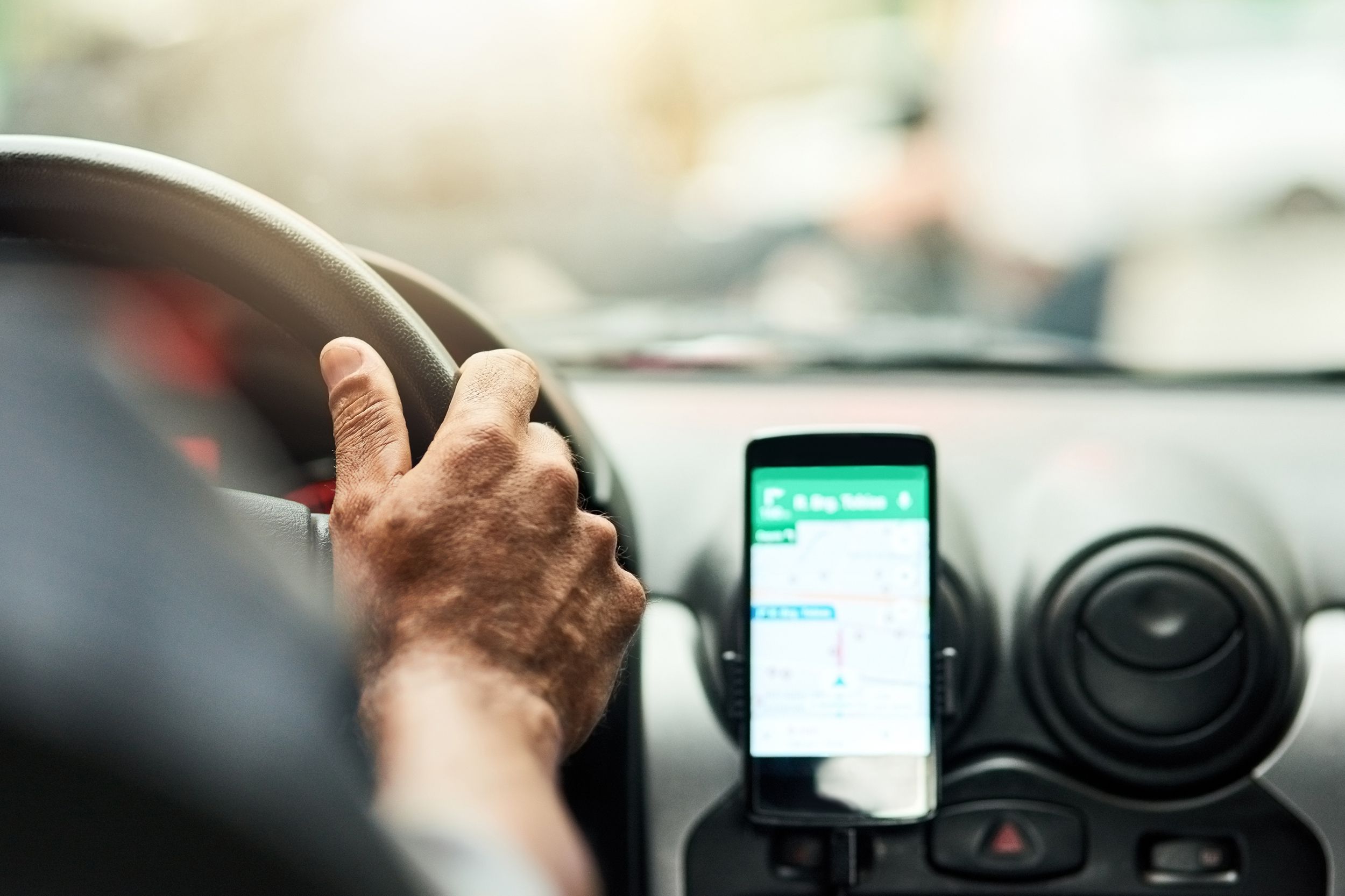 person driving car with GPS system on phone