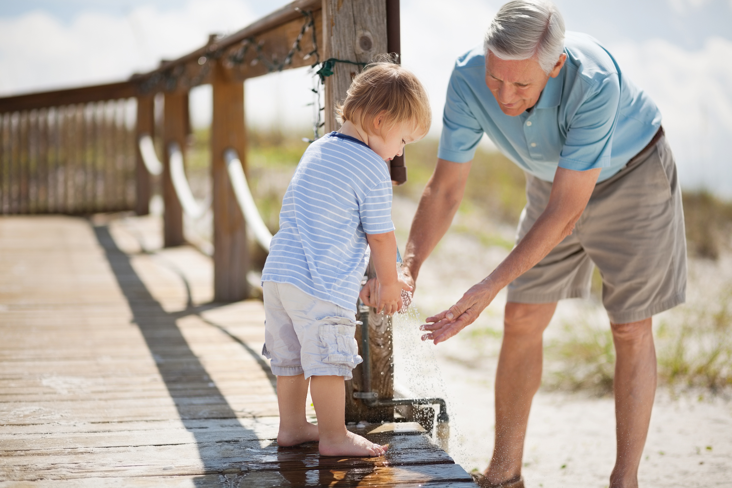 grandfather and boy washing hands at beach