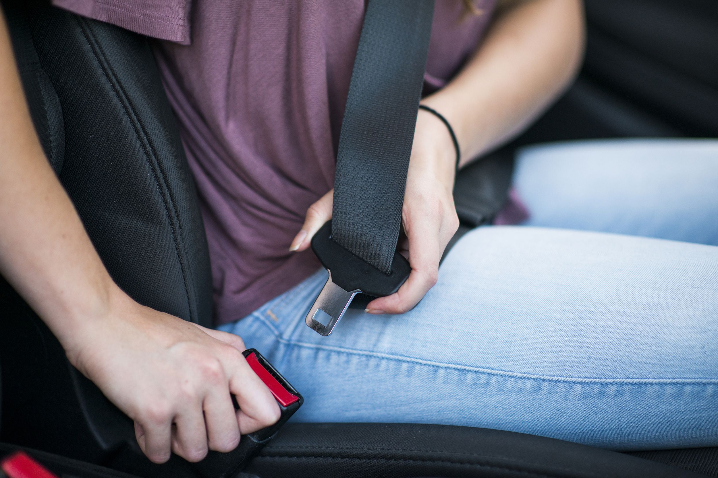 woman buckling seat belt in car