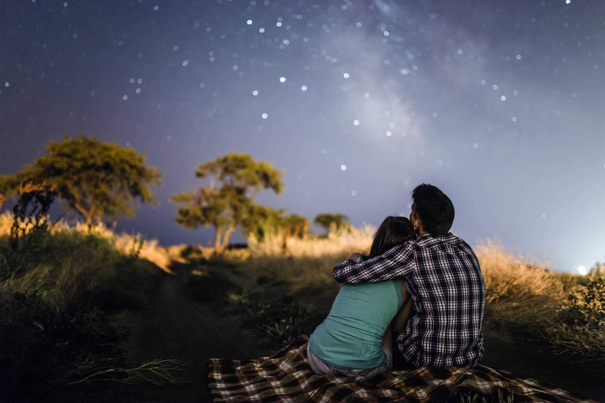 couple looking at stars sitting on blanket