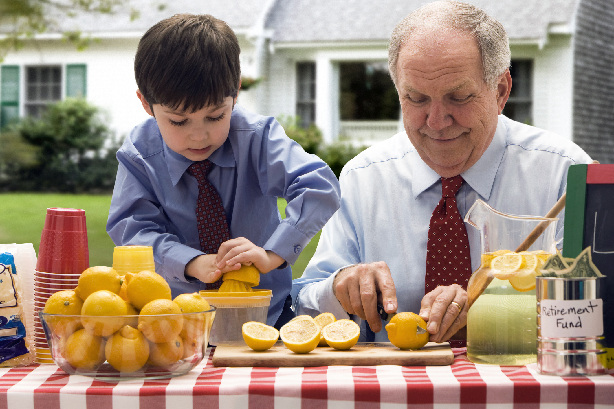 senior and child making lemonade in stand outside house