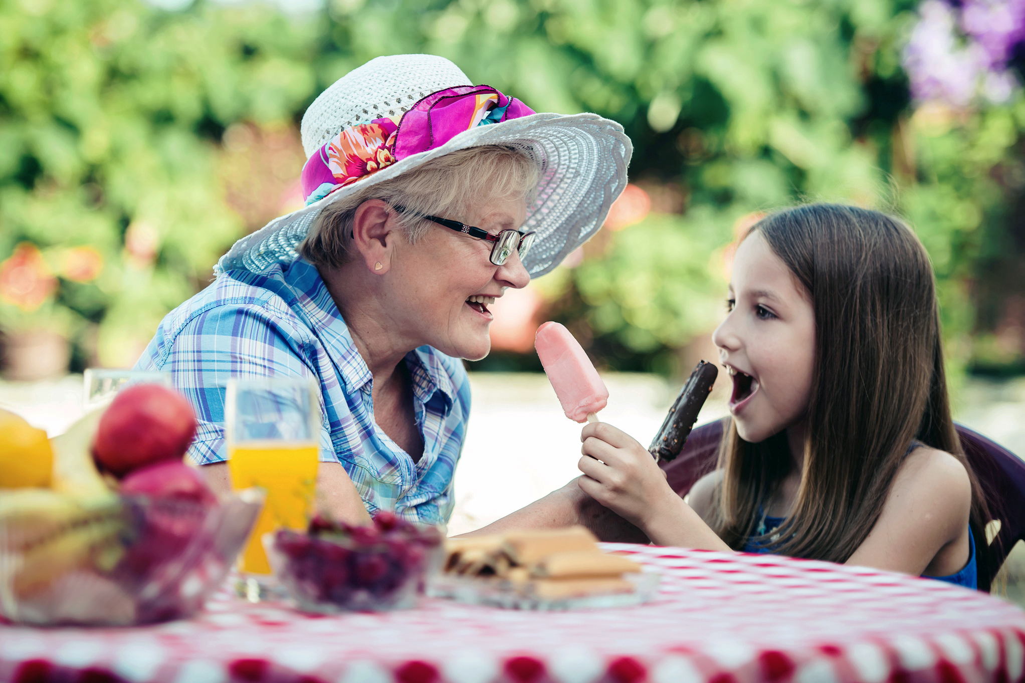 senior and child sharing popsicles in garden
