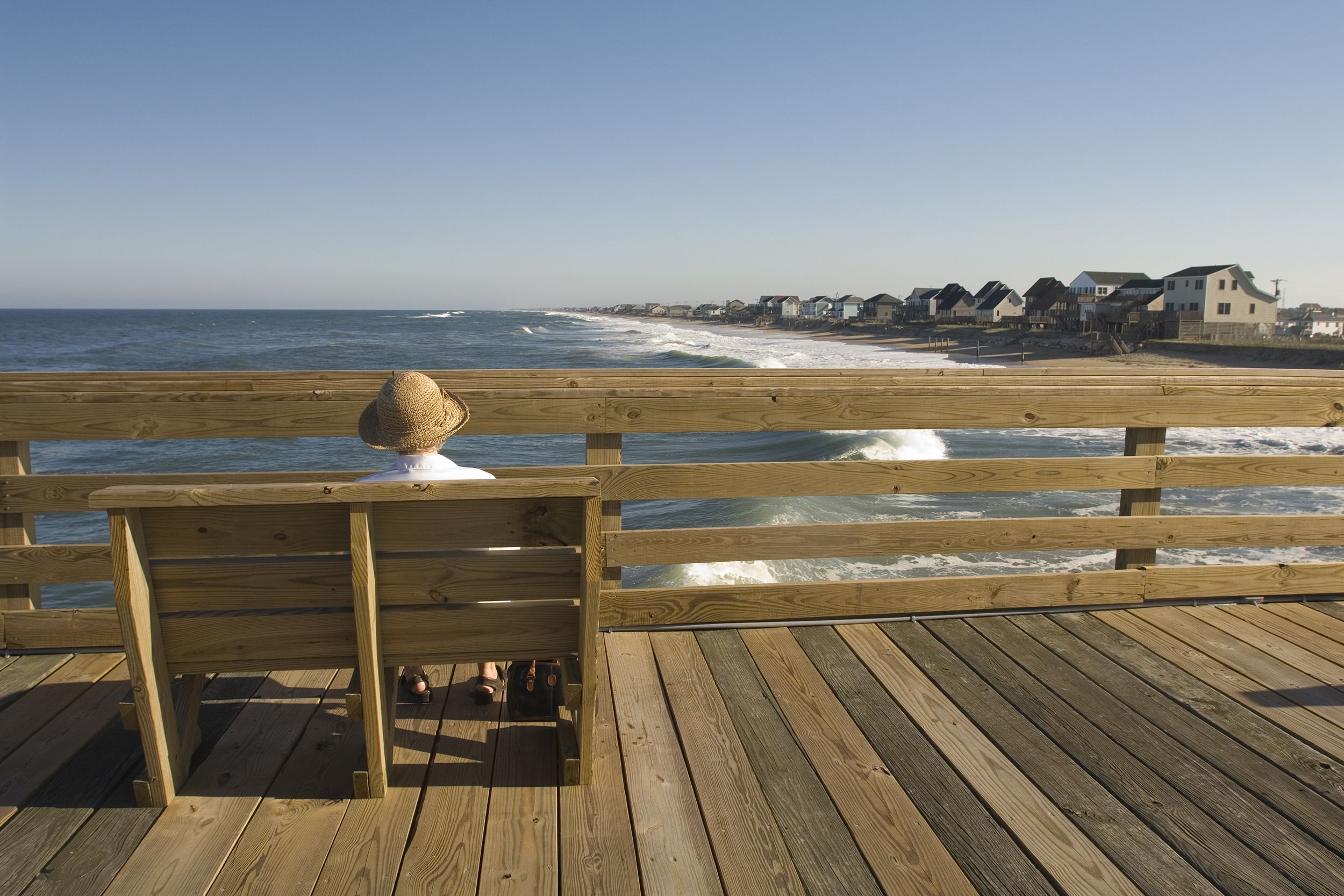 senior woman sitting on a bench watching the sea